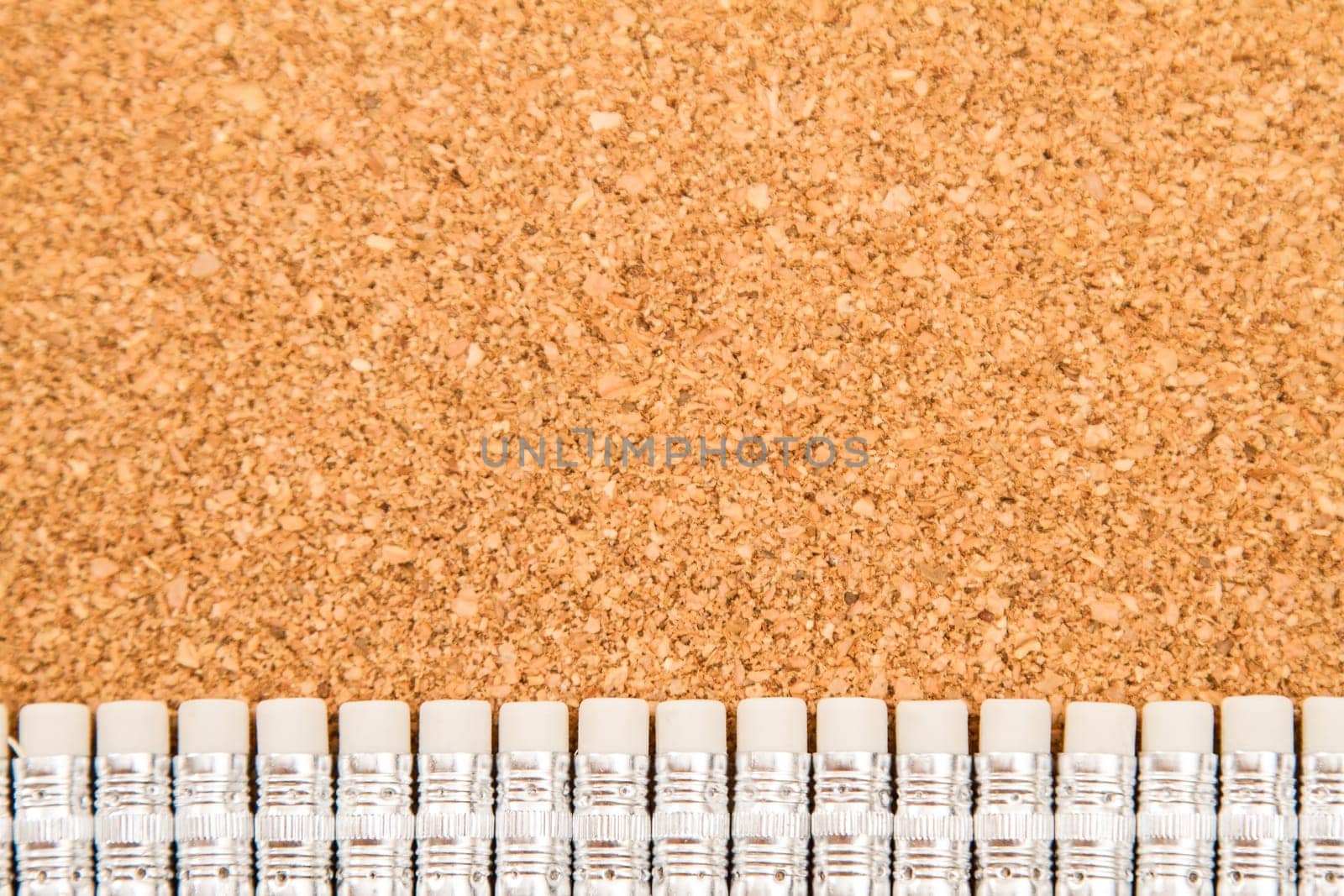 Bunch of pencils with rubbers over a cork board.