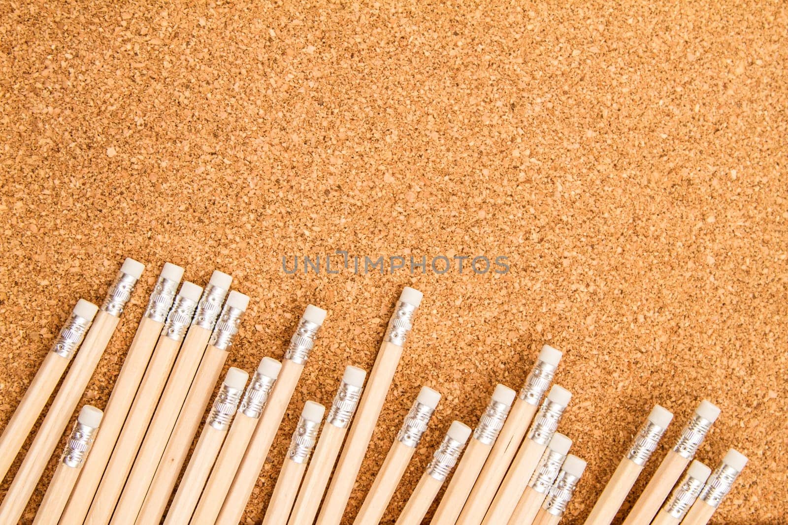 Bunch of wooden pencils over a cork board.