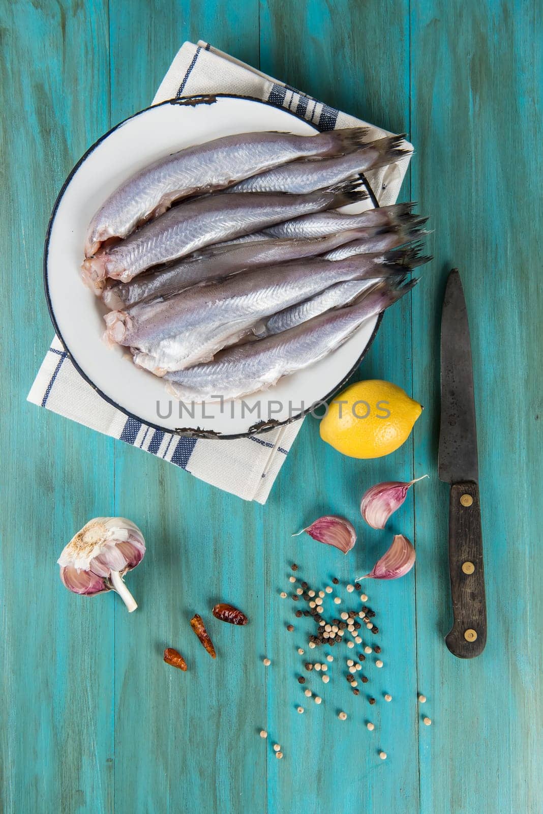 A plate with fish on the kitche table and ingredients to cook it.