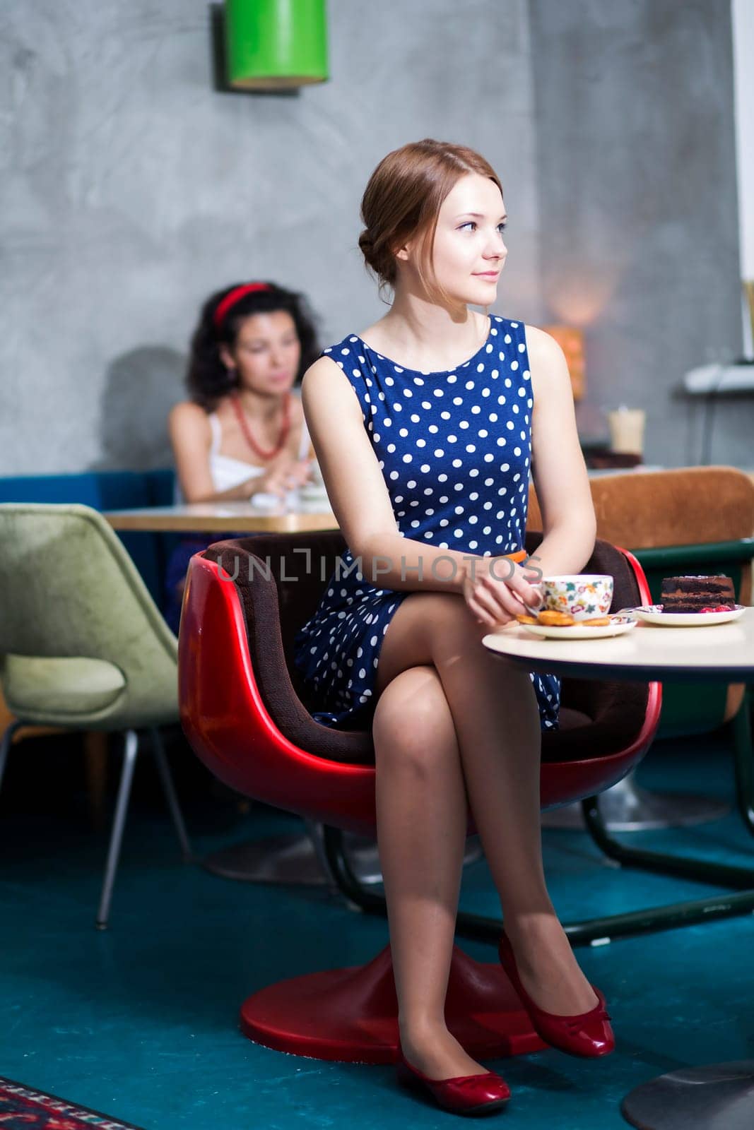 Woman in white spotted dress sit in cafe