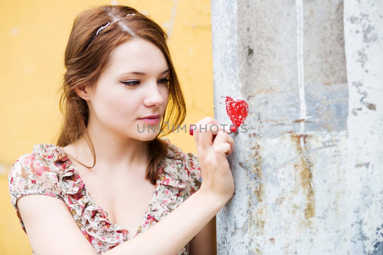 Woman in flowered dress draw heart on wall