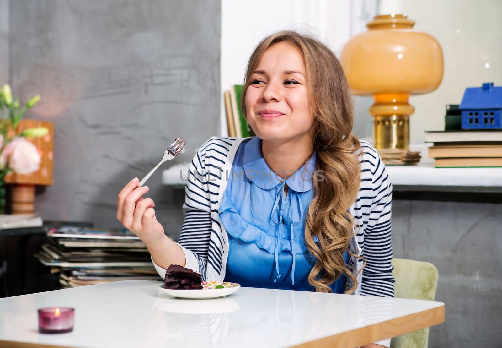 Woman at blue dress eat cake with fork