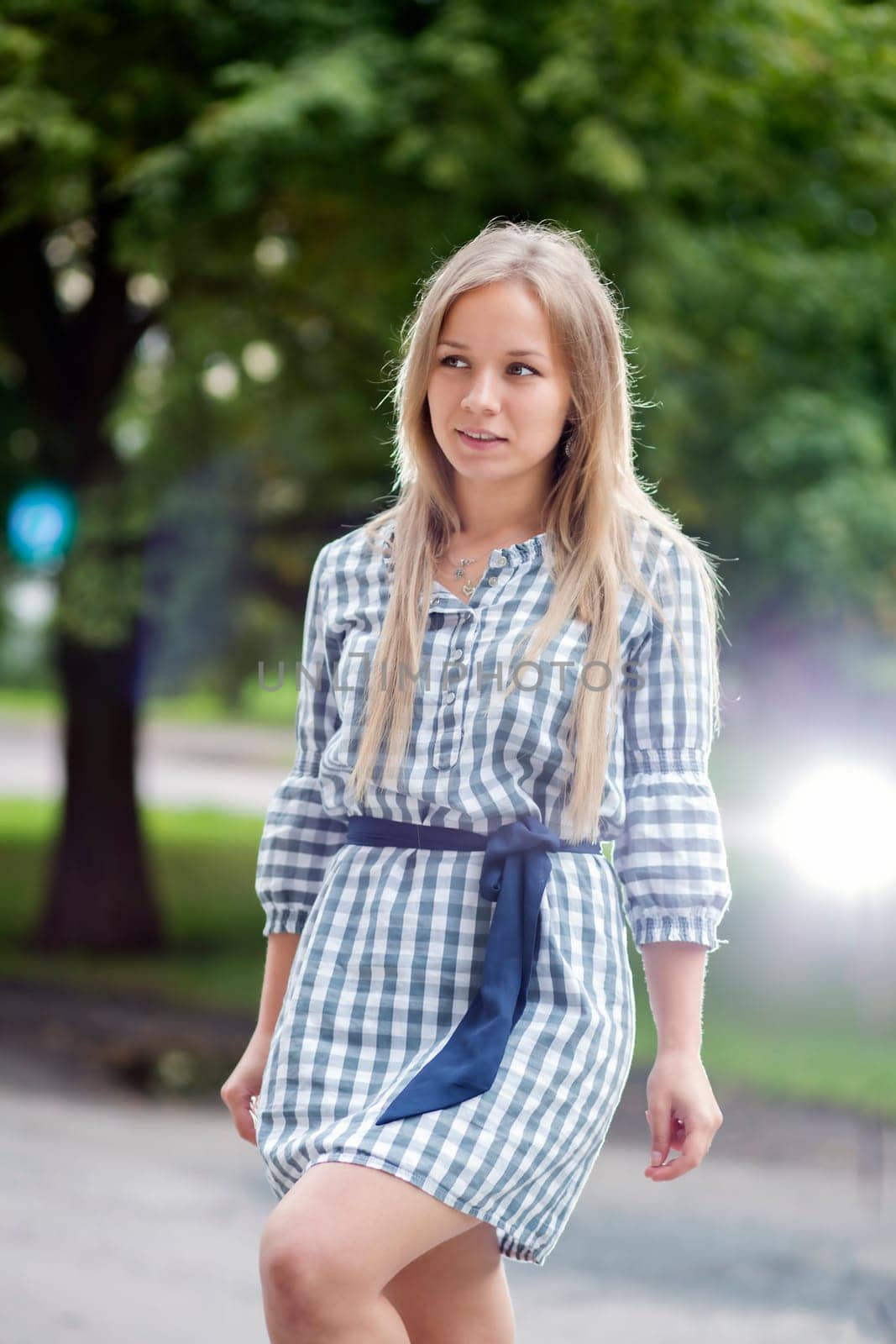 Woman in checkered dress walking in city park