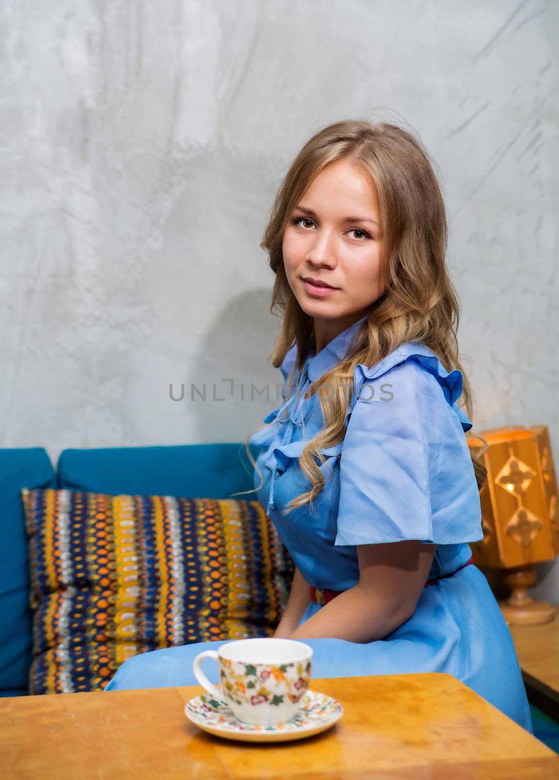 Woman at blue dress sit at squared table