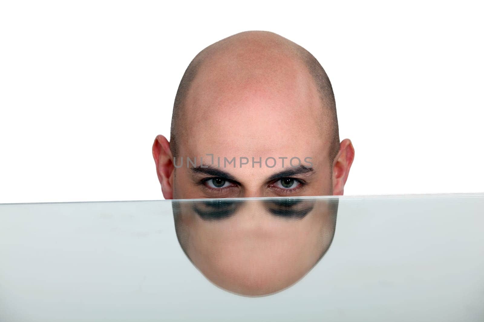 Bald man's head mirrored in a table