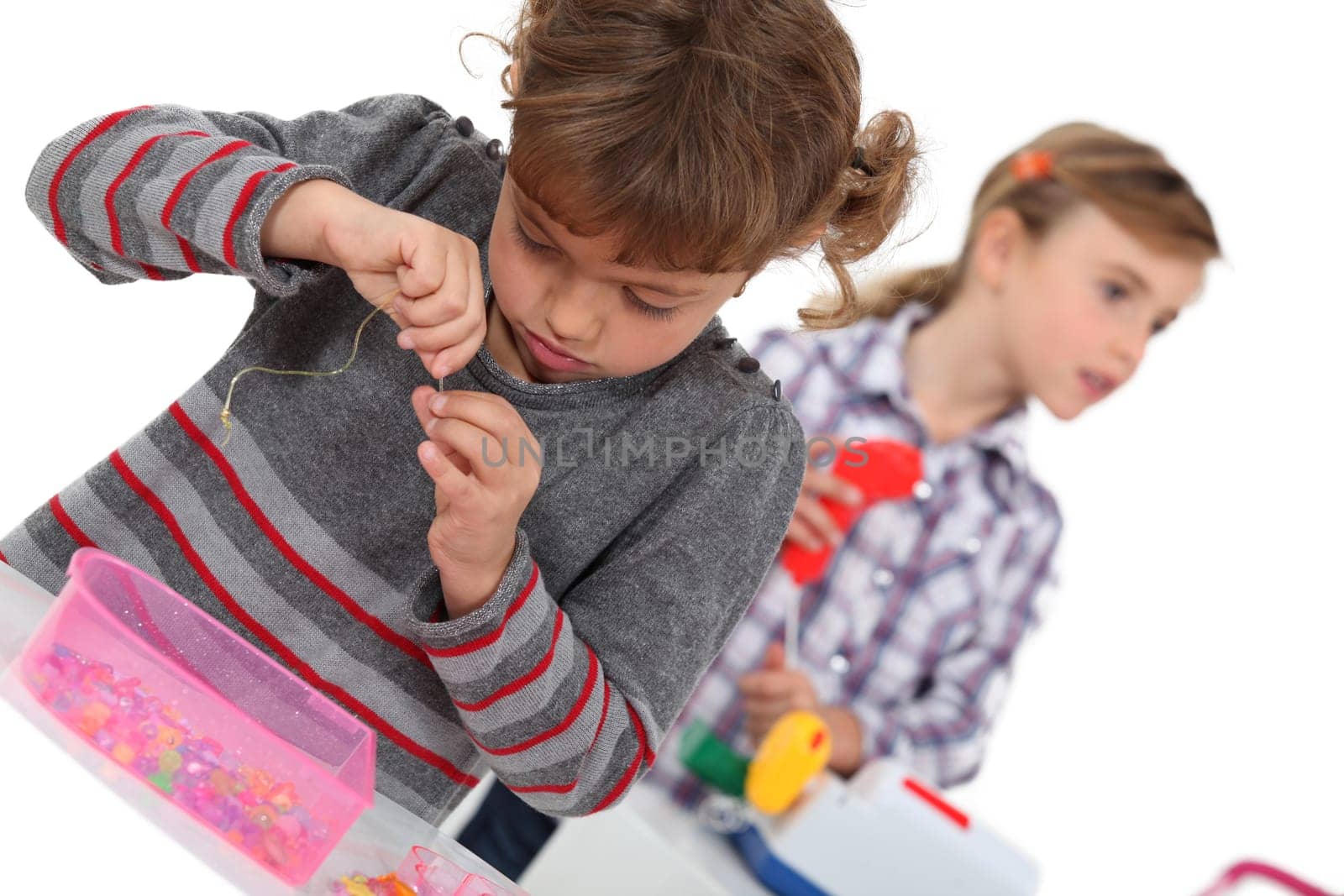 Young girl putting a thread through the eye of a needle