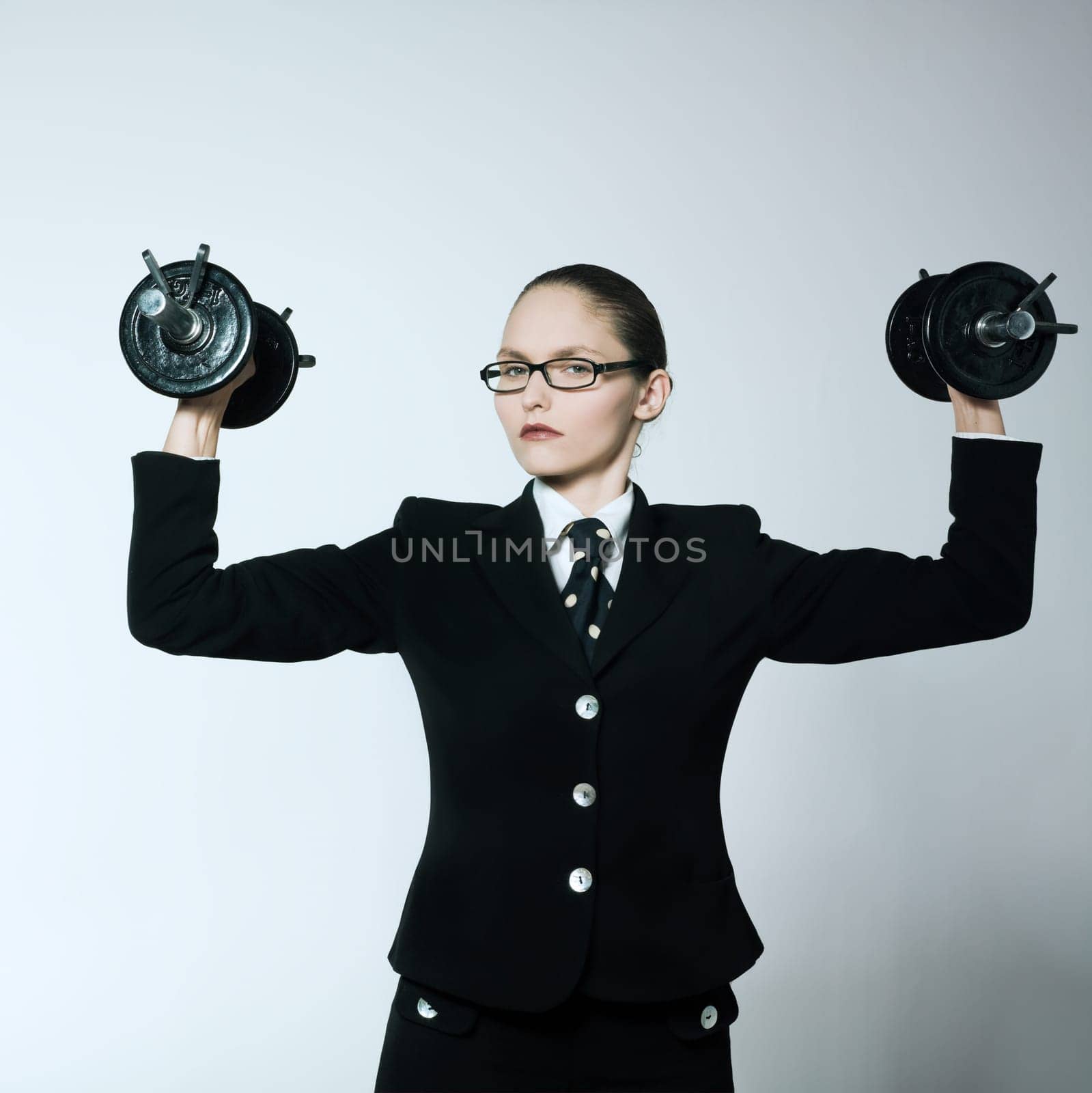 studio shot portrait of one caucasian young bsuiness woman holding weights
