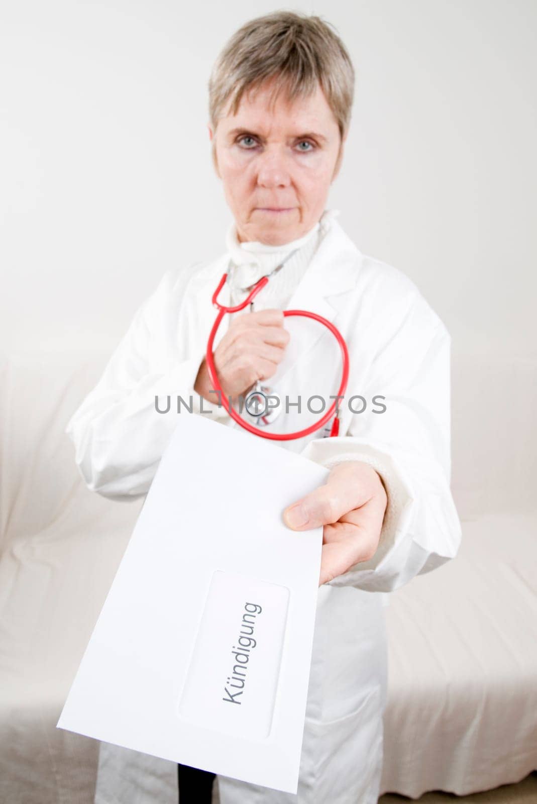 elderly doctor hands over her resignation in an envelope with a serious look towards the camera