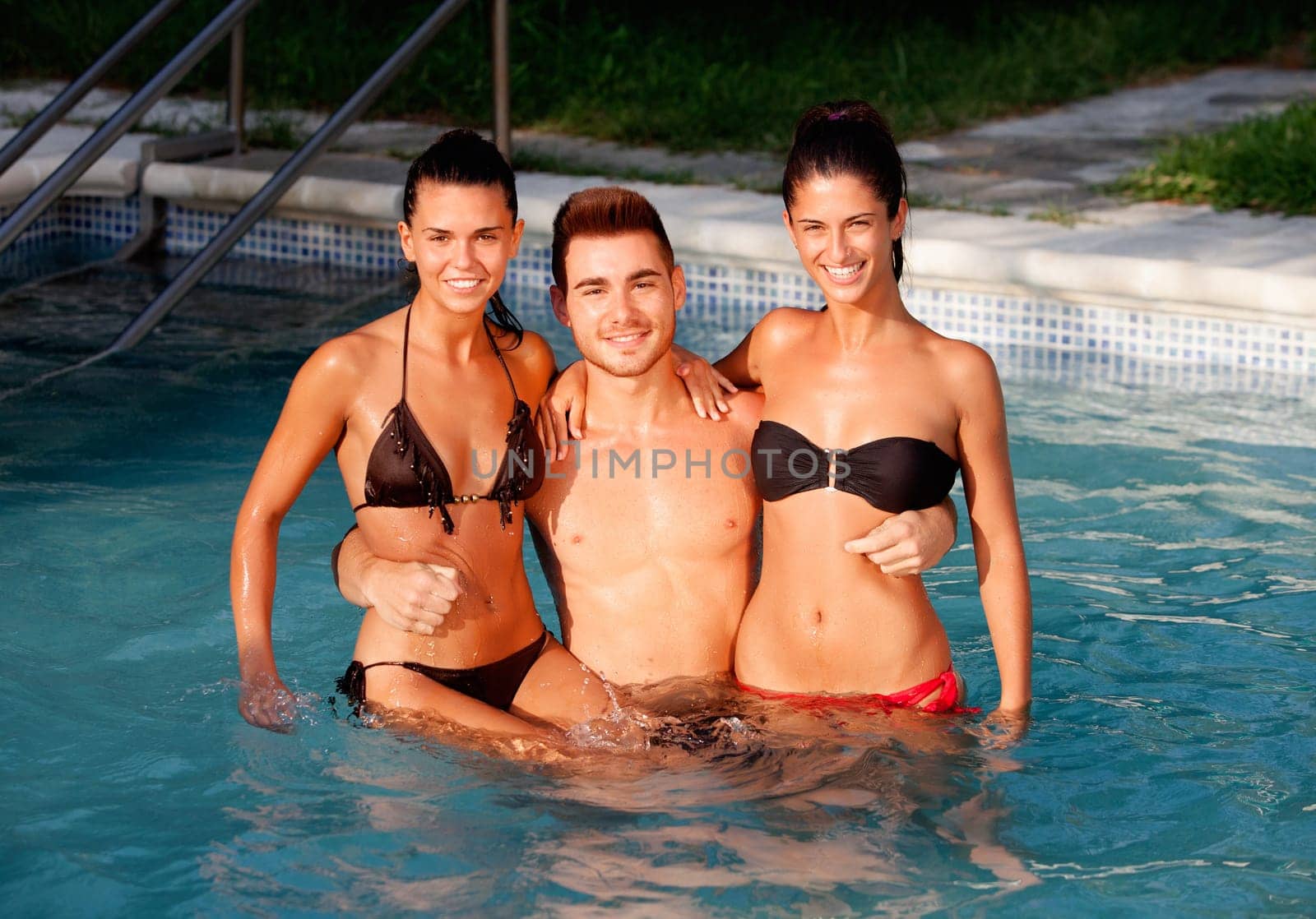 Three happy friends in the pool with a blue water of background