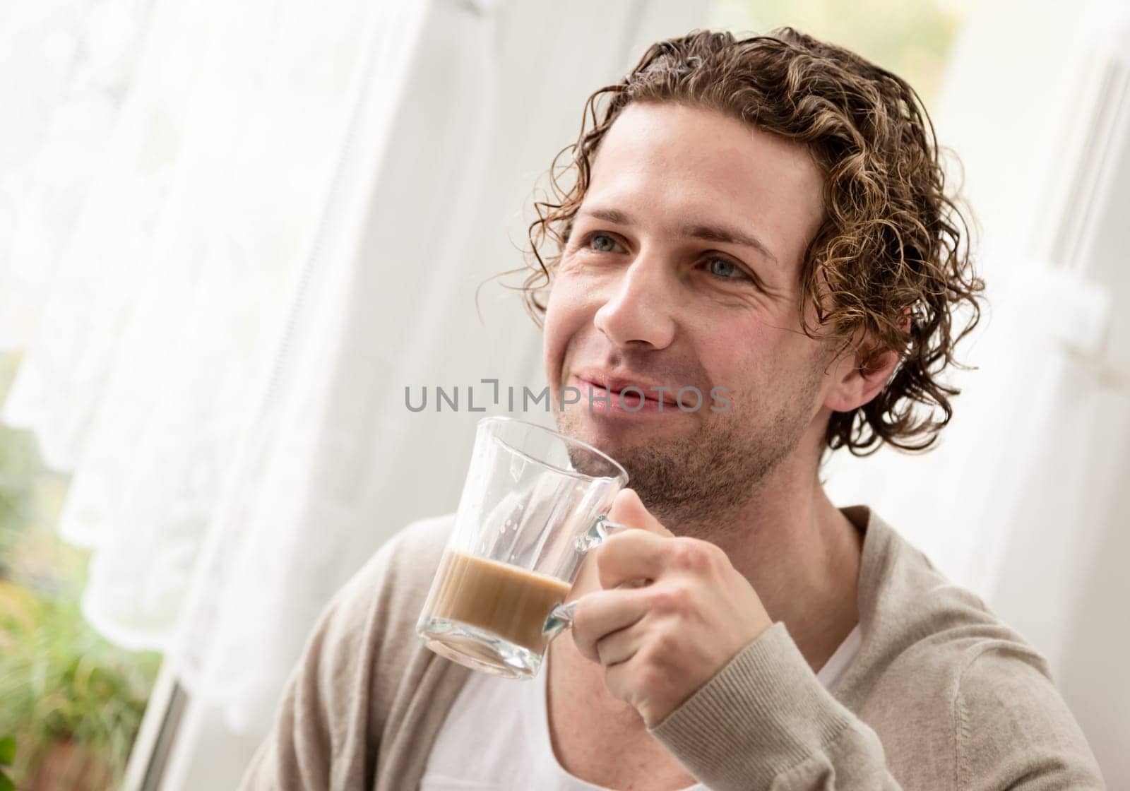 Portrait of a young woman with coffee at the window at home