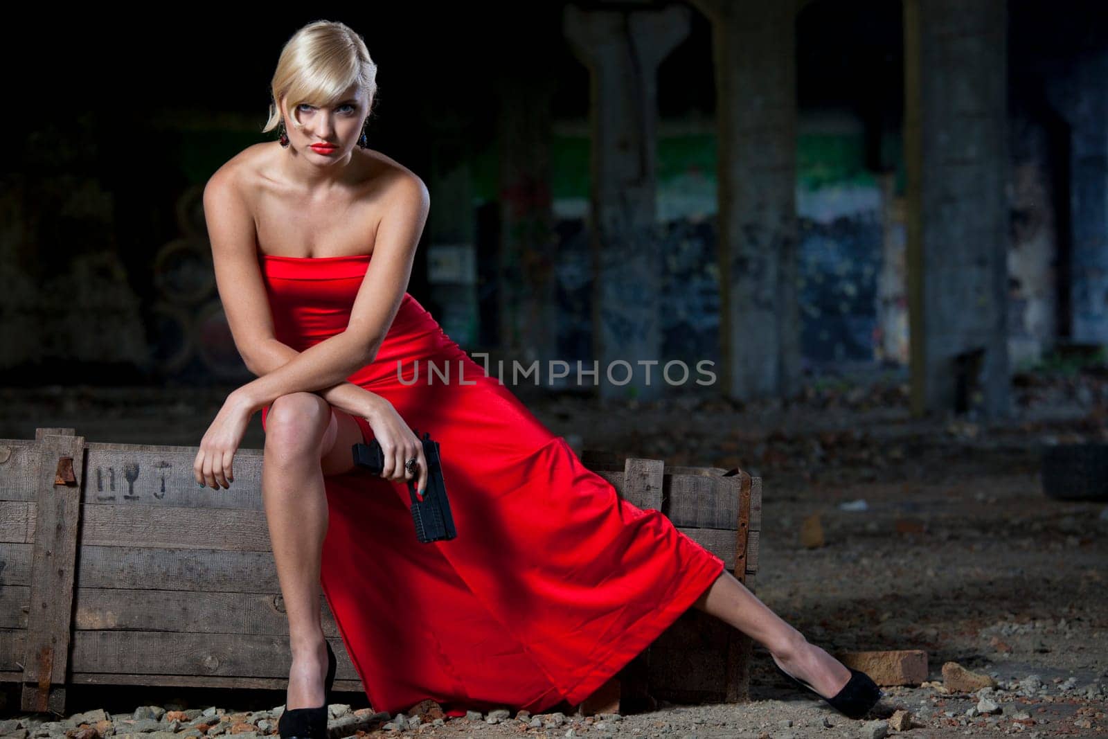 Woman in vintage look sitting on military box in old fabric ruins