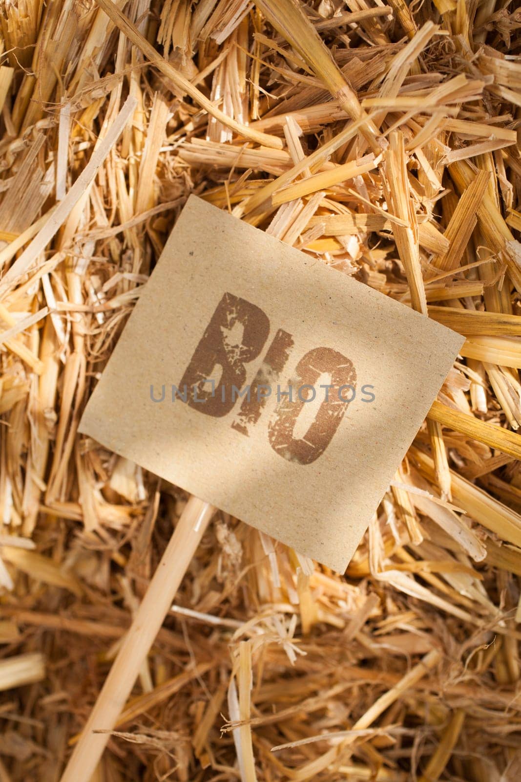 Rustic vertical close-up of a 'bio' tag on straw