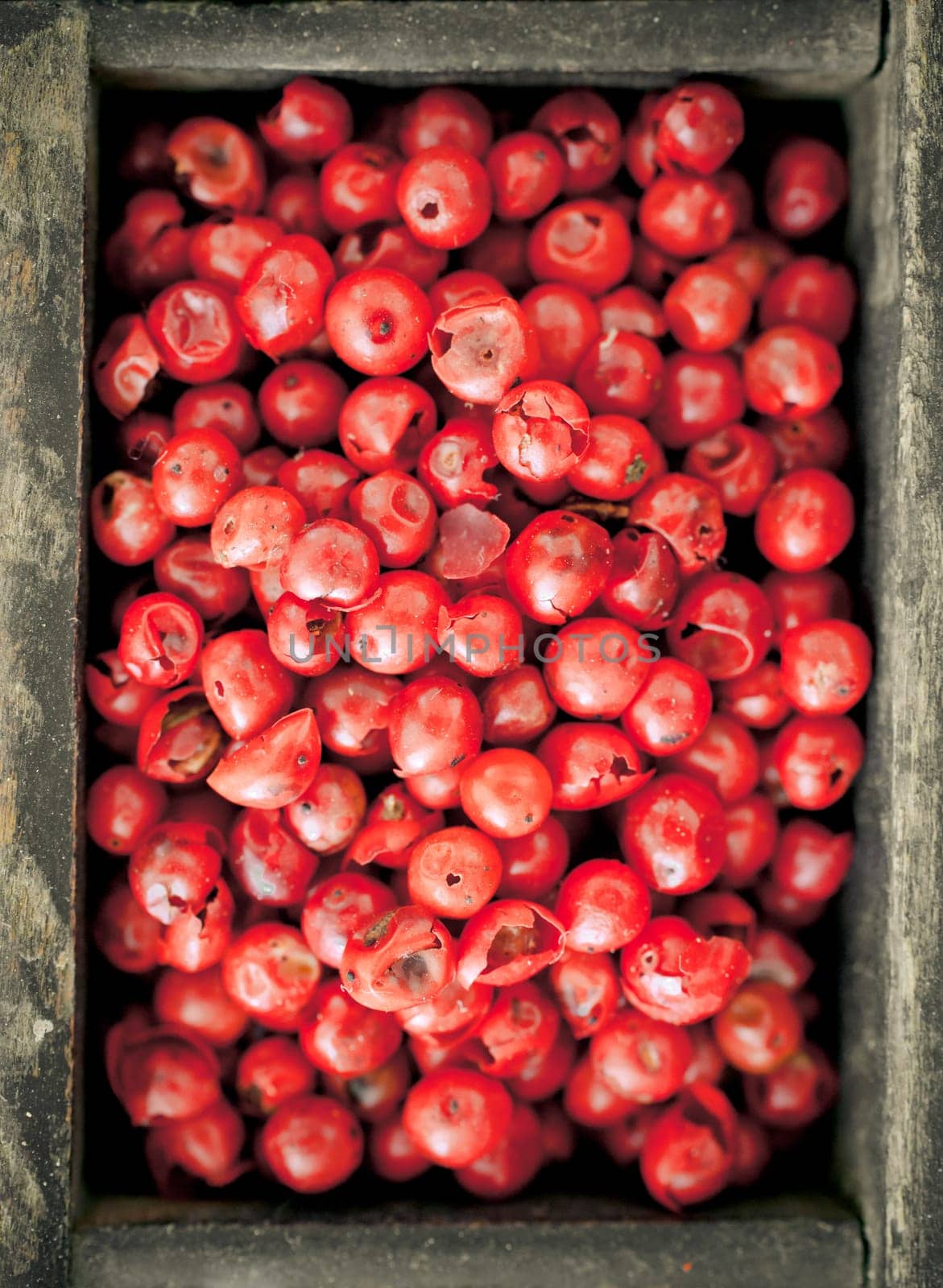 Colourful whole dried pink peppercorns with their red colouring used as a pungent spice and condiment in cooking, overhead view