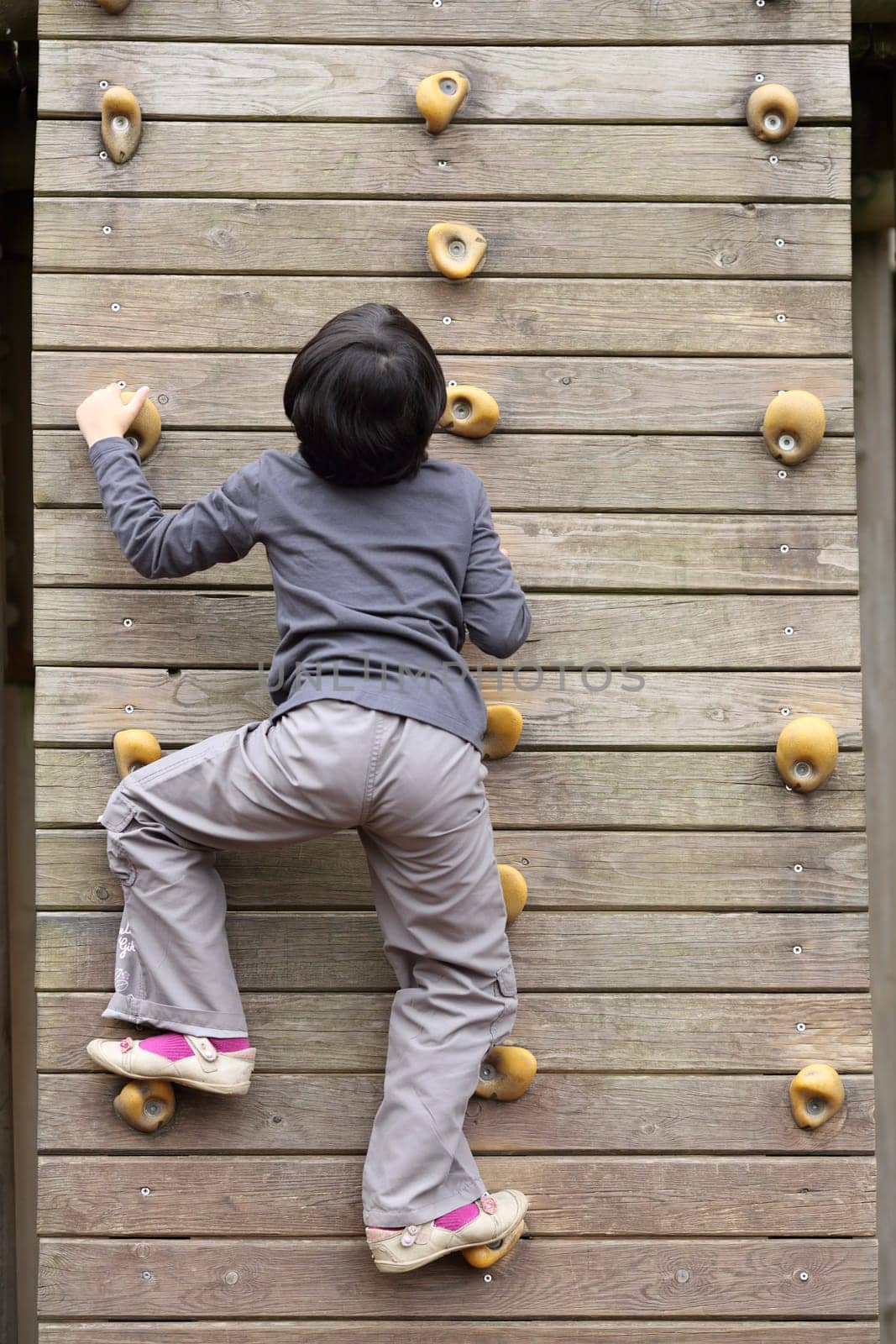 Details of an outdoors climbing girl on a climbing wall for kid