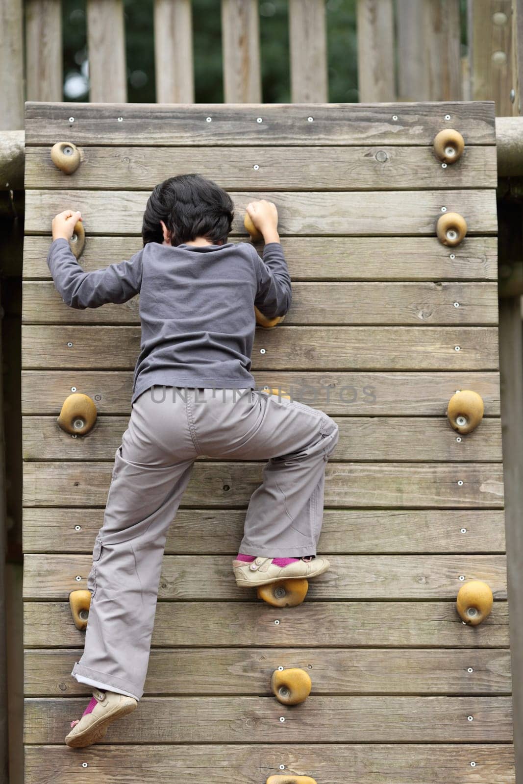 Details of an outdoors climbing girl on a climbing wall for kid