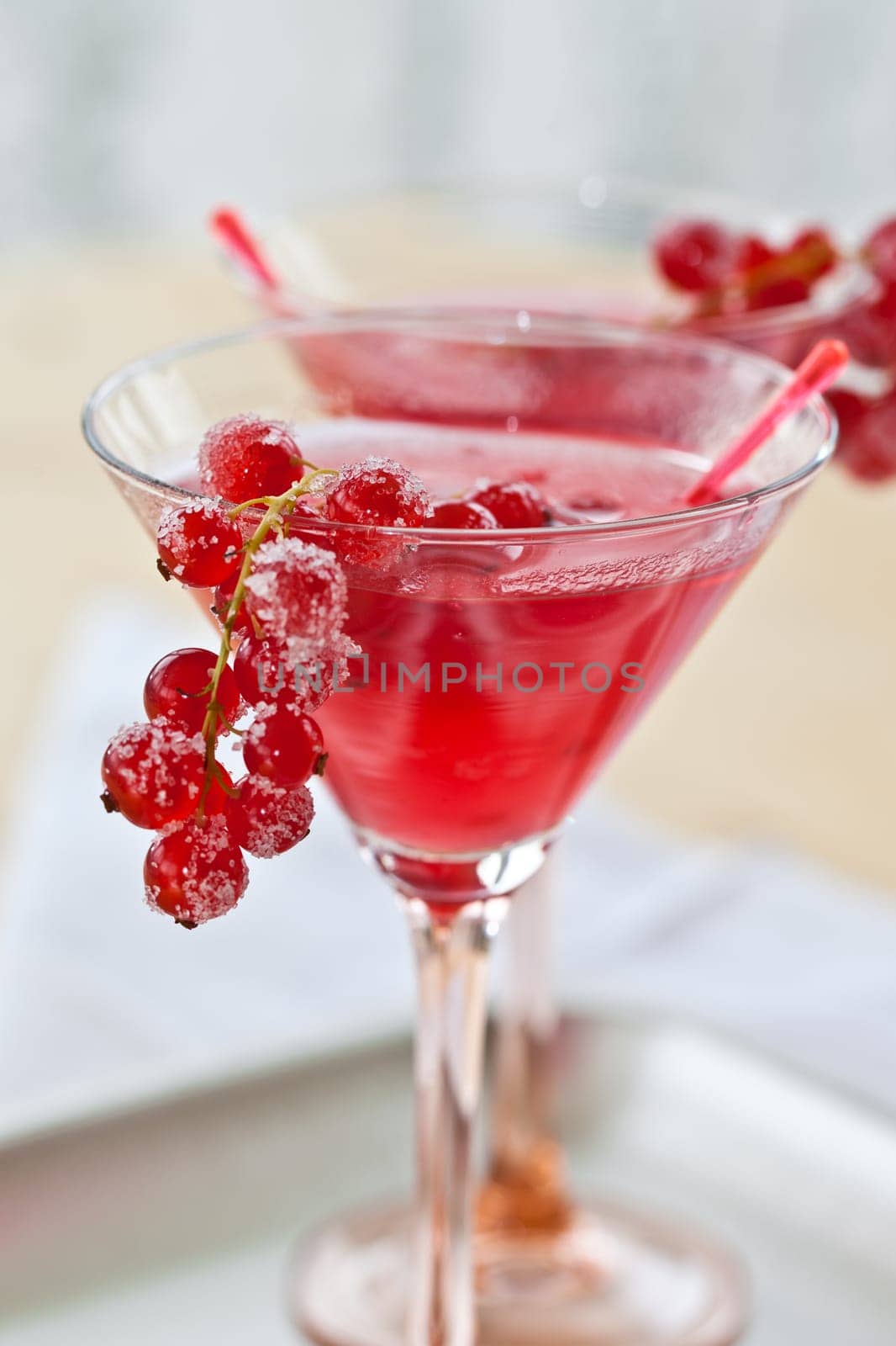 Red cocktail in a stem jar with fresh currants