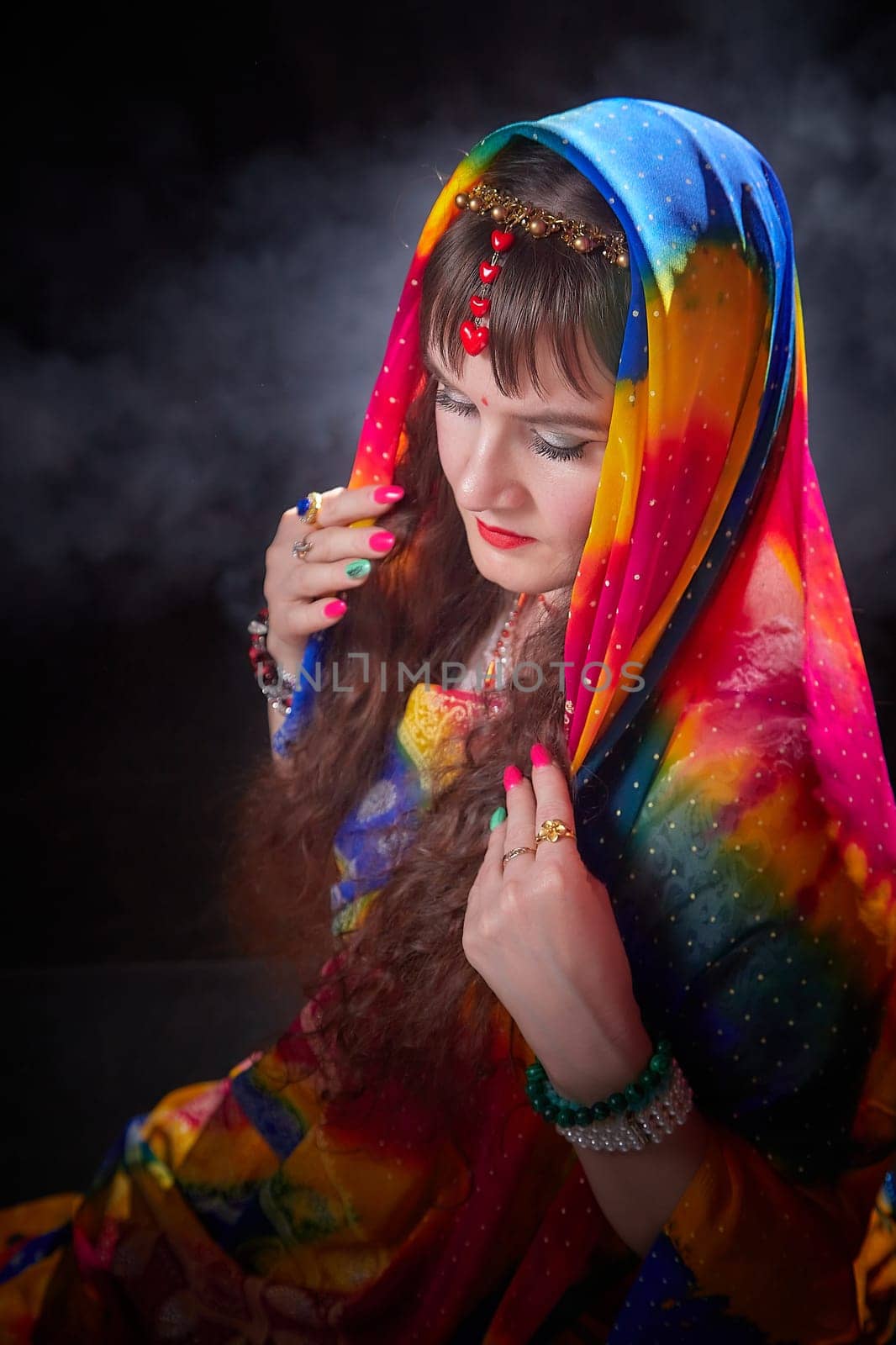 A mature woman models a beautifully colored sari while gracefully posing and showcasing Indian cultural elements in a chic setting.