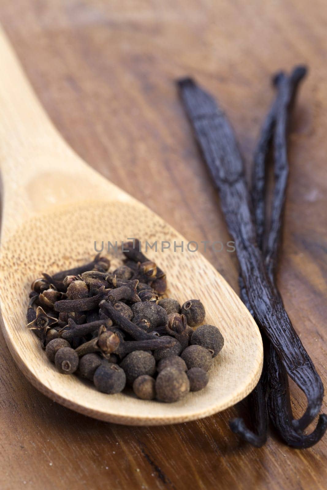 Spices on a wooden spoon,next to vanilla pods
