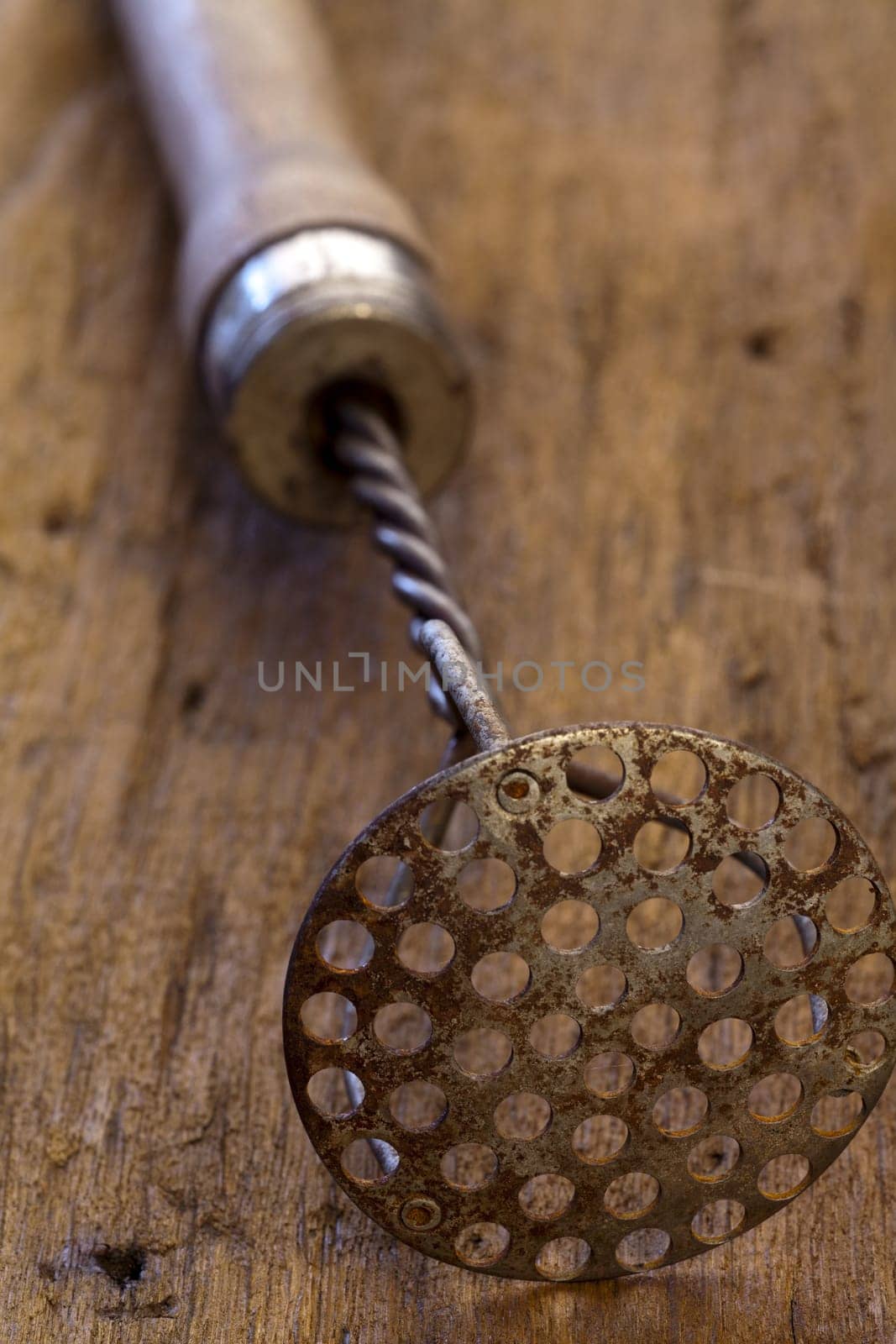 Old potato masher on rustic wooden table