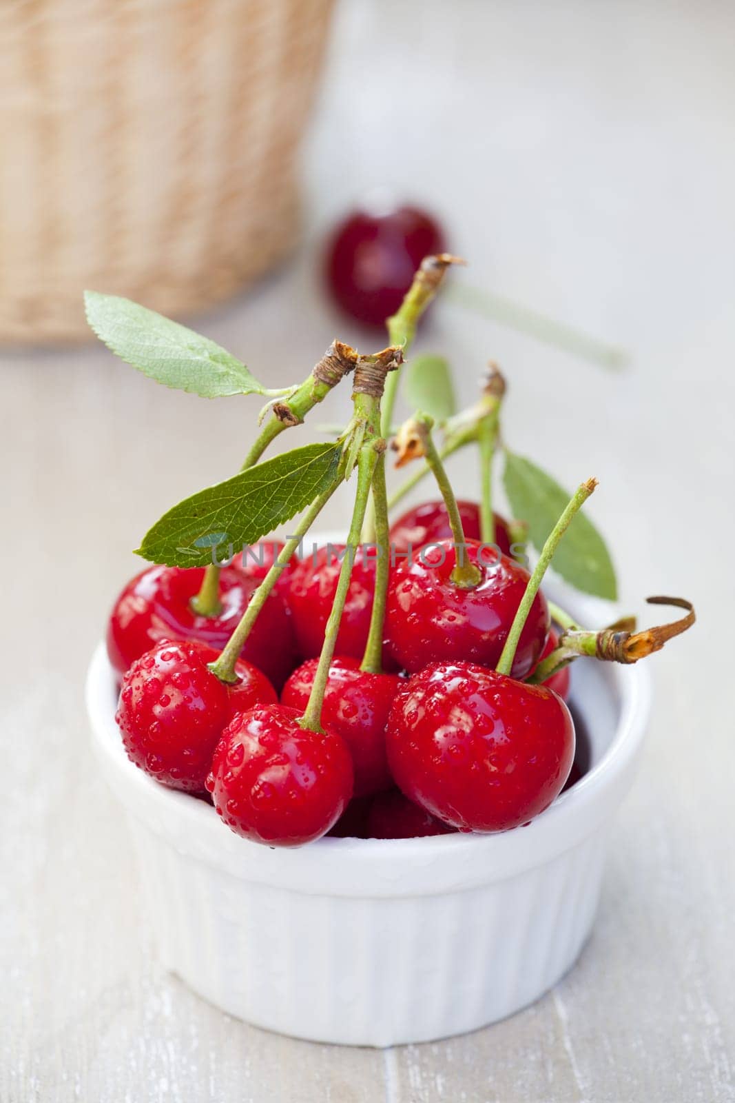 Bowl with cherries and a cherry in the background