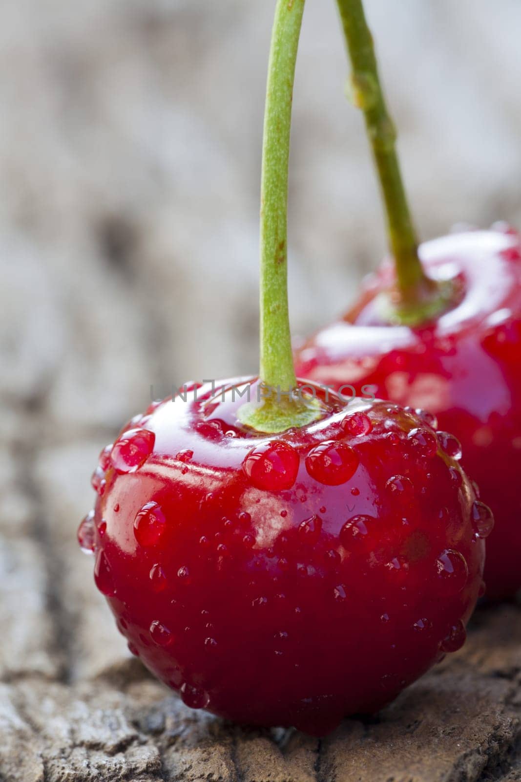 Two cherries with drops of water on wooden surface