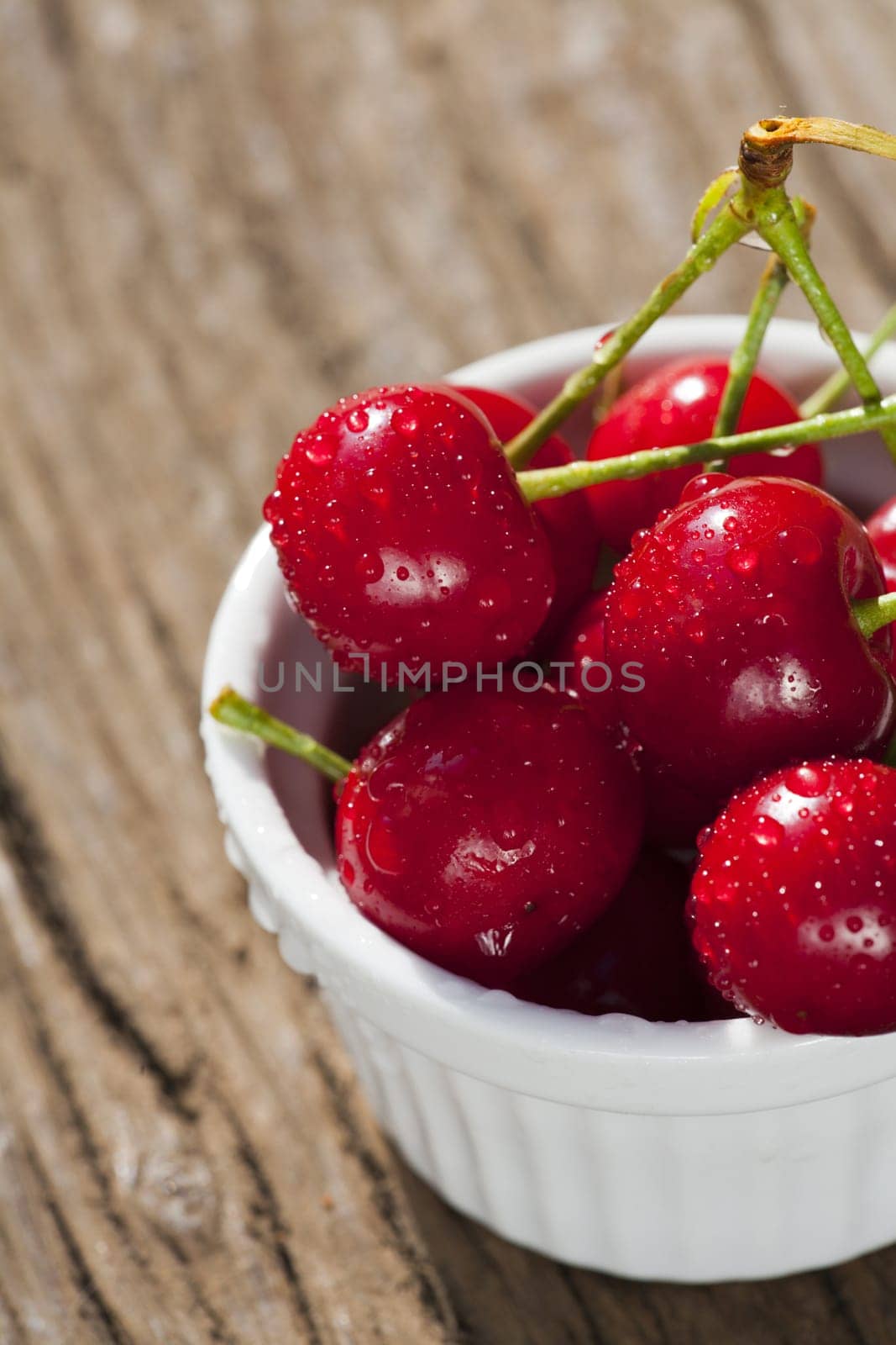 Bowl of ripe cherries on wooden table