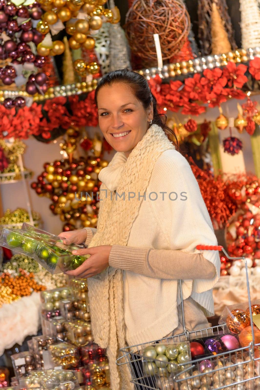 Cheerful woman buyer shopping Christmas ornaments with shopping basket