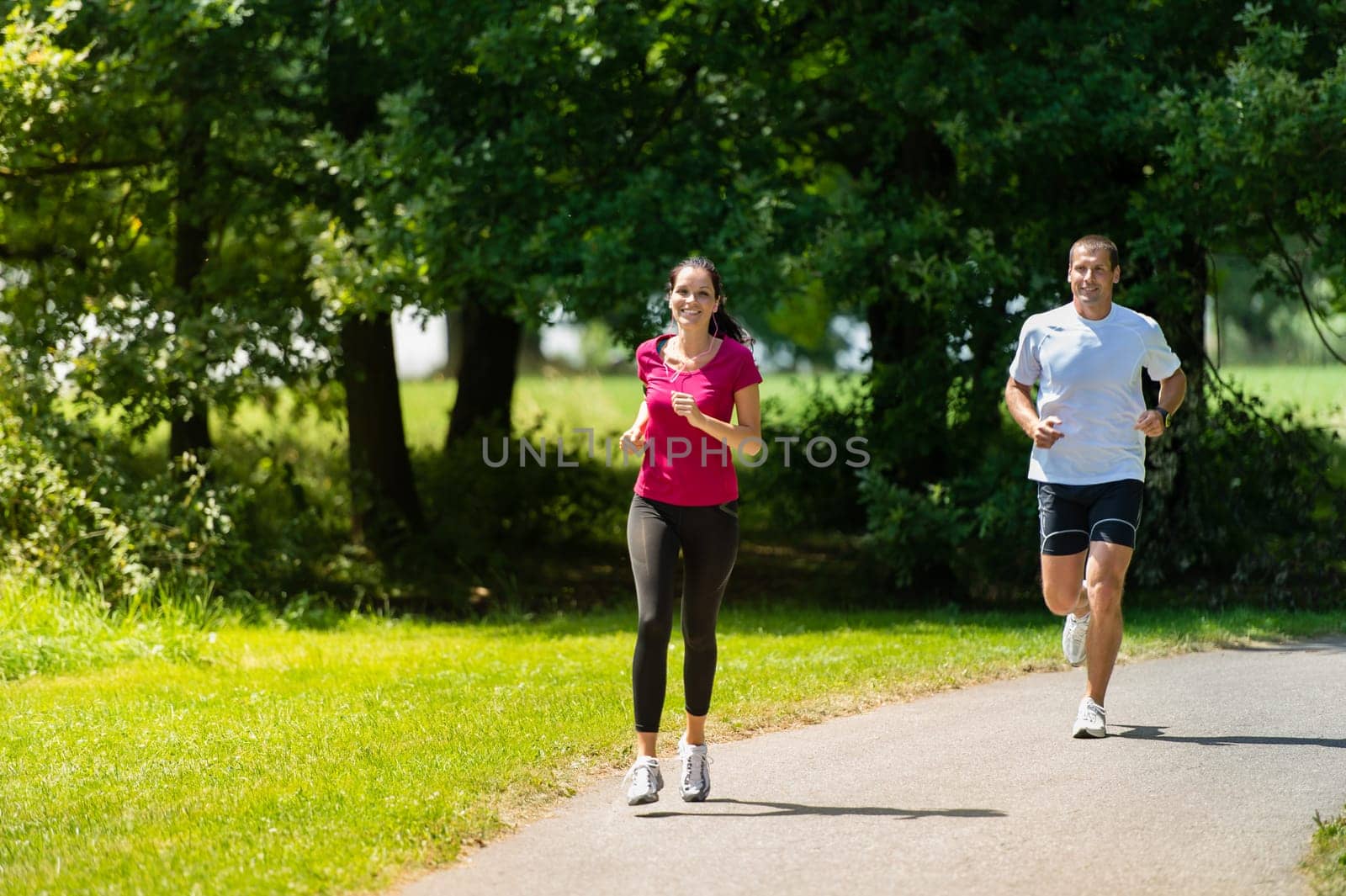 Caucasian boyfriend and girlfriend running a race in sunny park