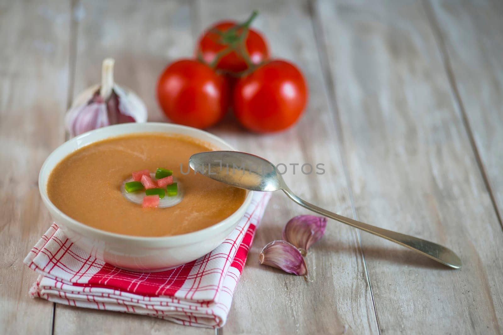 A bowl with gazpacho soup on a wooden background