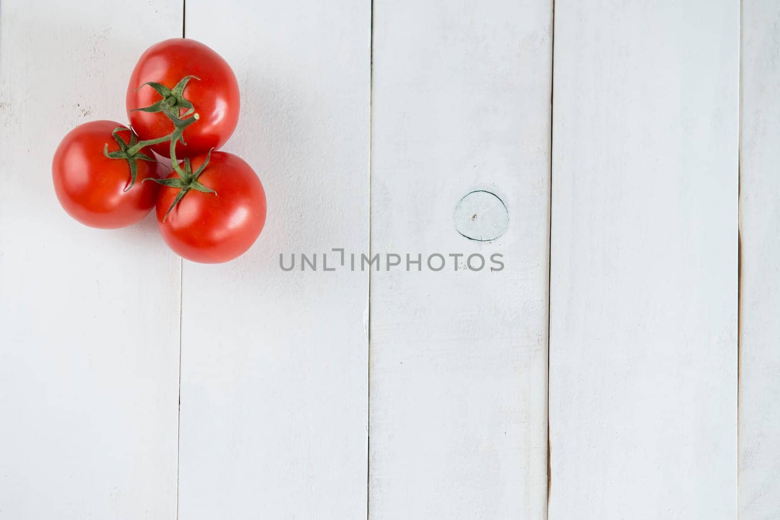 Three tomatoes over a white wooden background