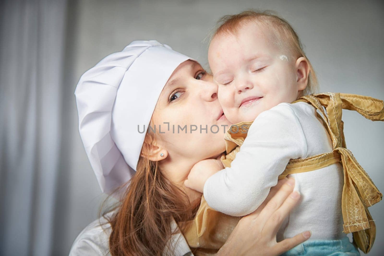 A mother and daughter joyfully engage in a flour-filled moment, creating memories in a cozy kitchen setting.