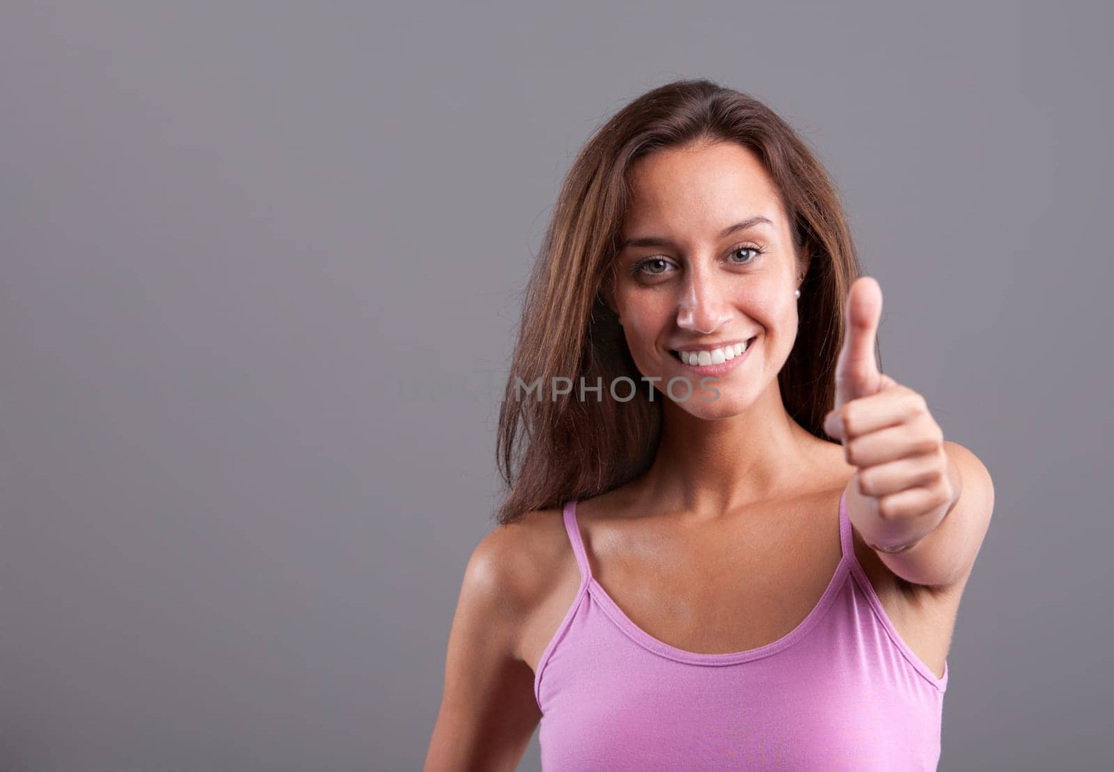 Mediterranean beautiful girl smiling and expressing positivity with her OK thumbs up
