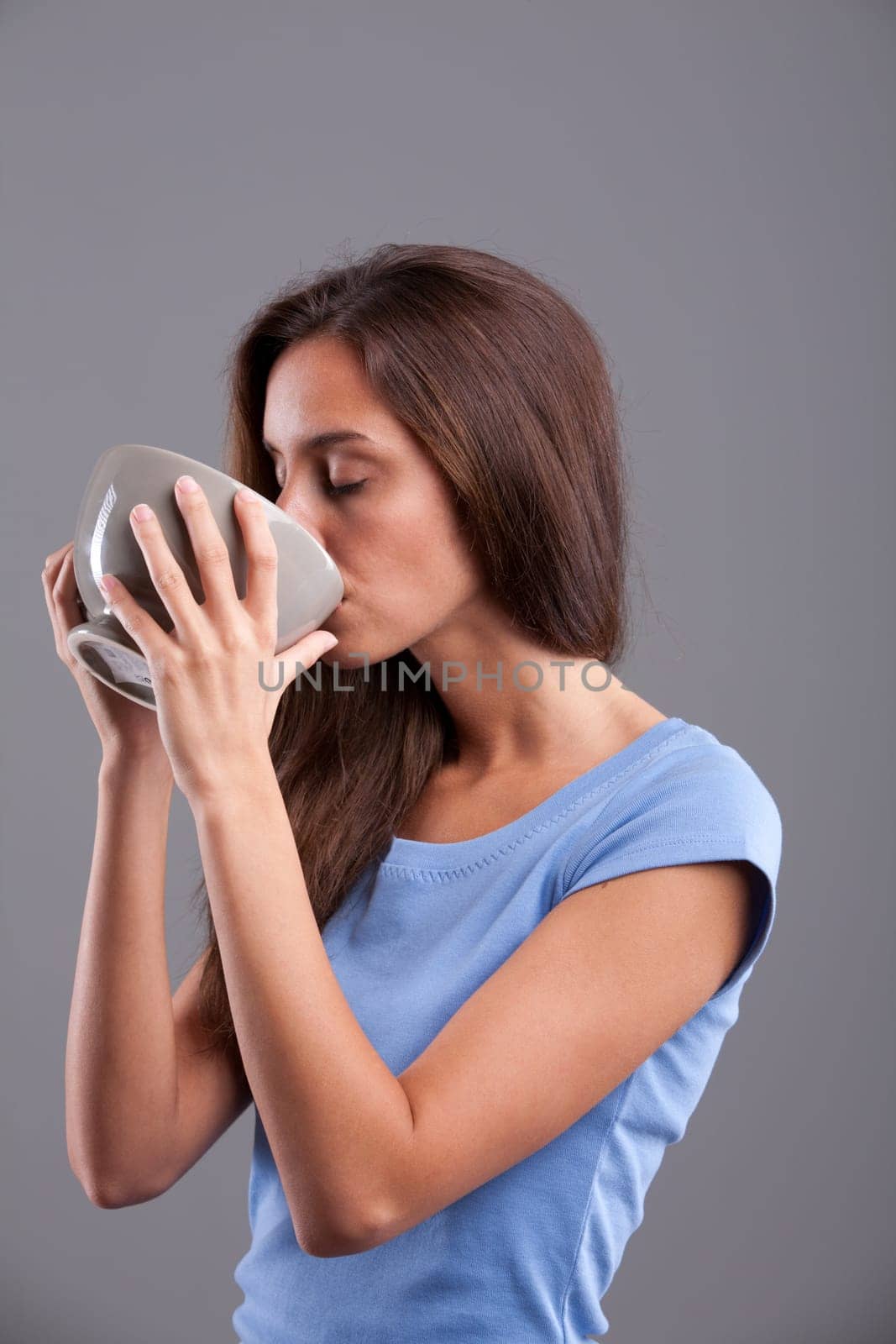 Beautiful young woman drinking from a mugful for breakfast