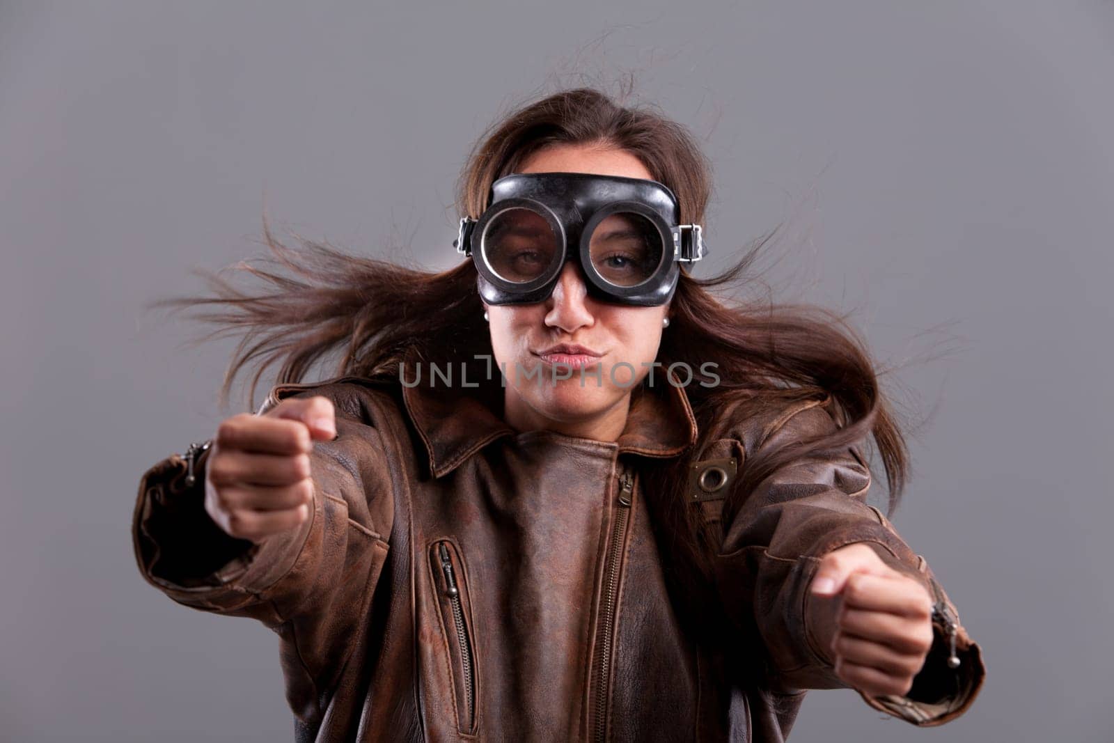 Funny girl with motorbiker big glasses and a leather jacket pretending to blow