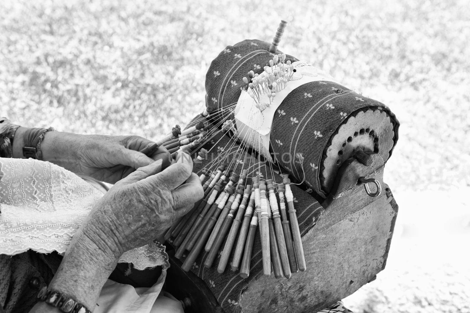 Close-up of an elderly spanish woman demonstrating the intricate art of making pillow lace or bobbin lace.