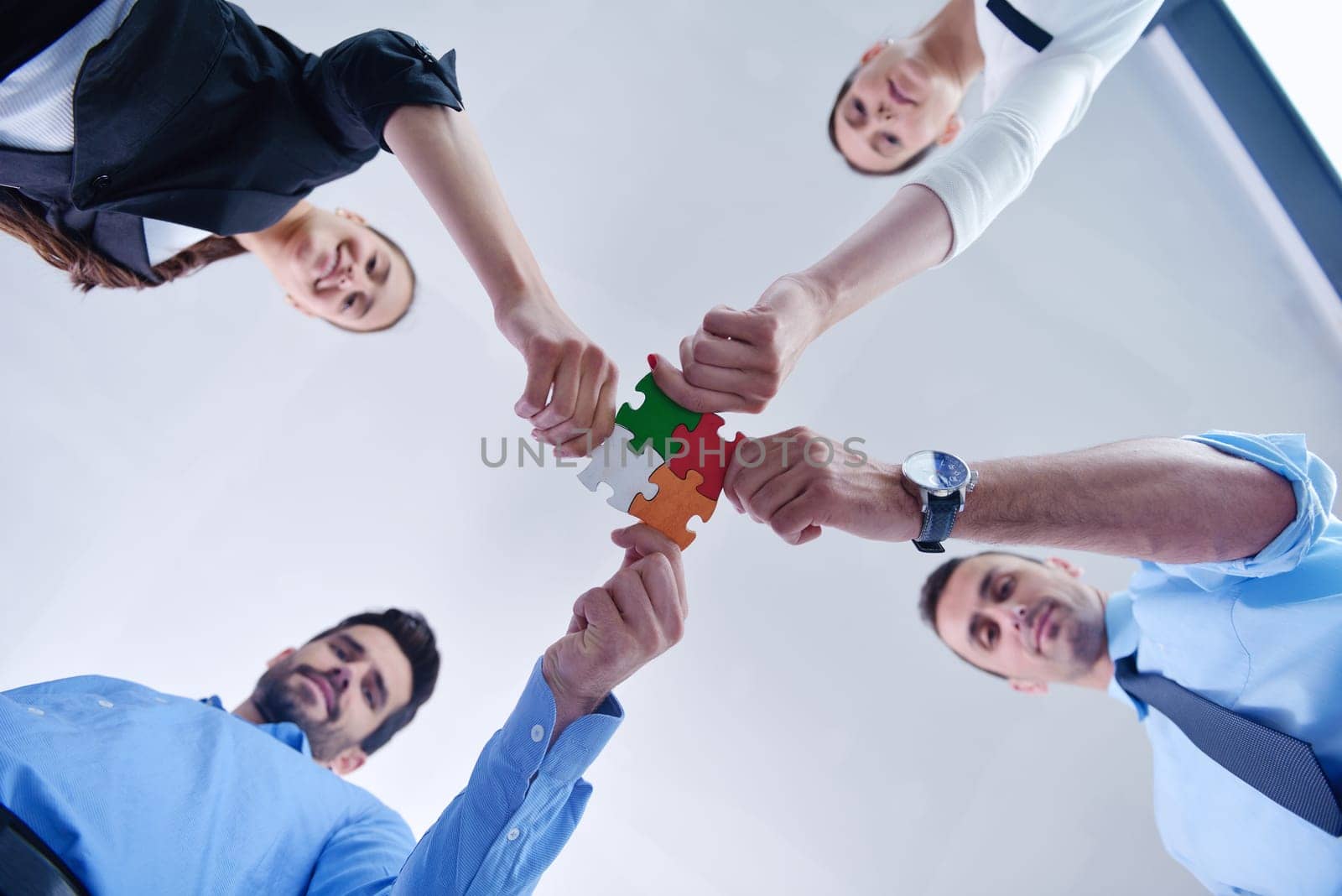Group of business people assembling jigsaw puzzle and represent team support and help concept