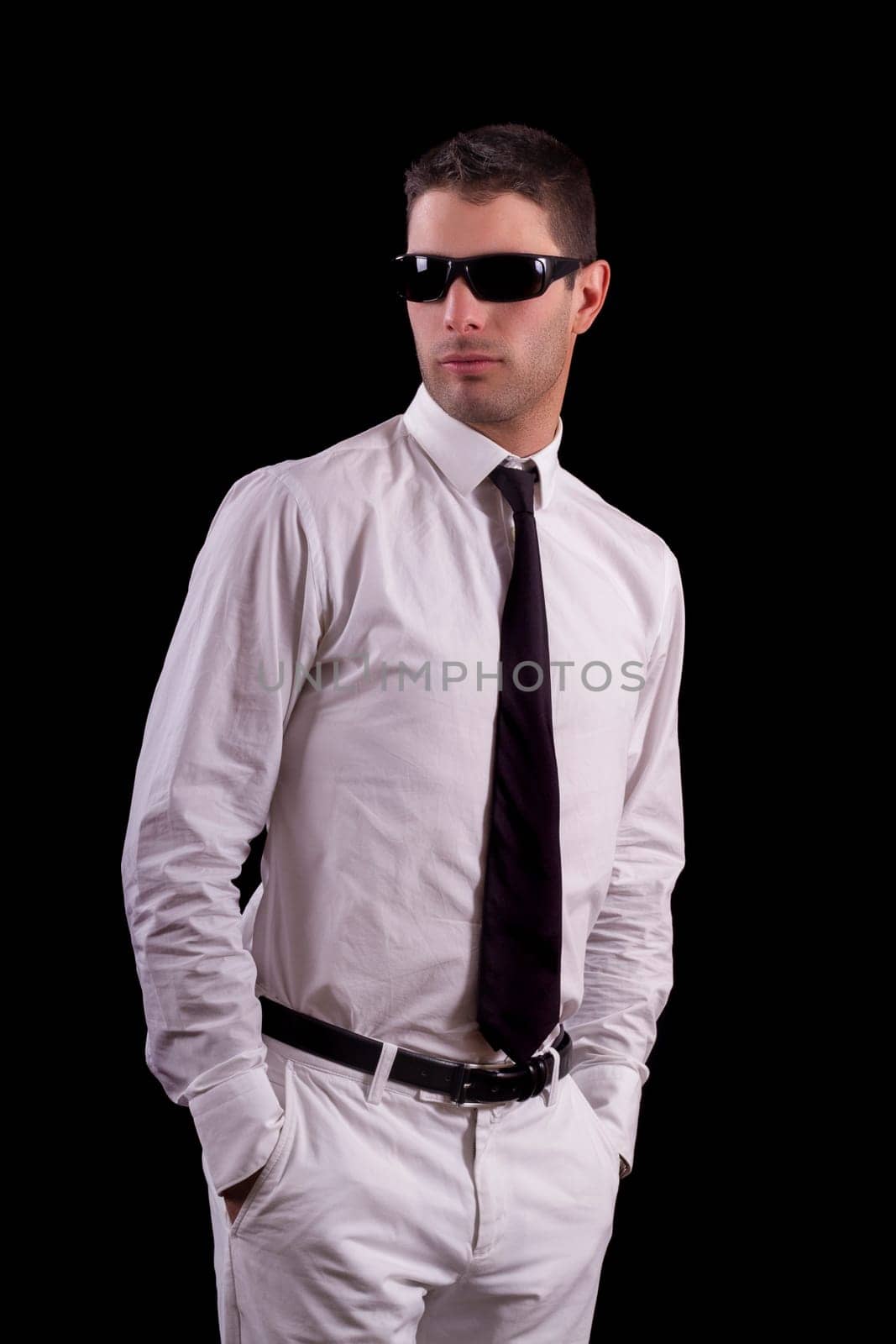 View of a handsome young man on a white suit with tie isolated on a black background.