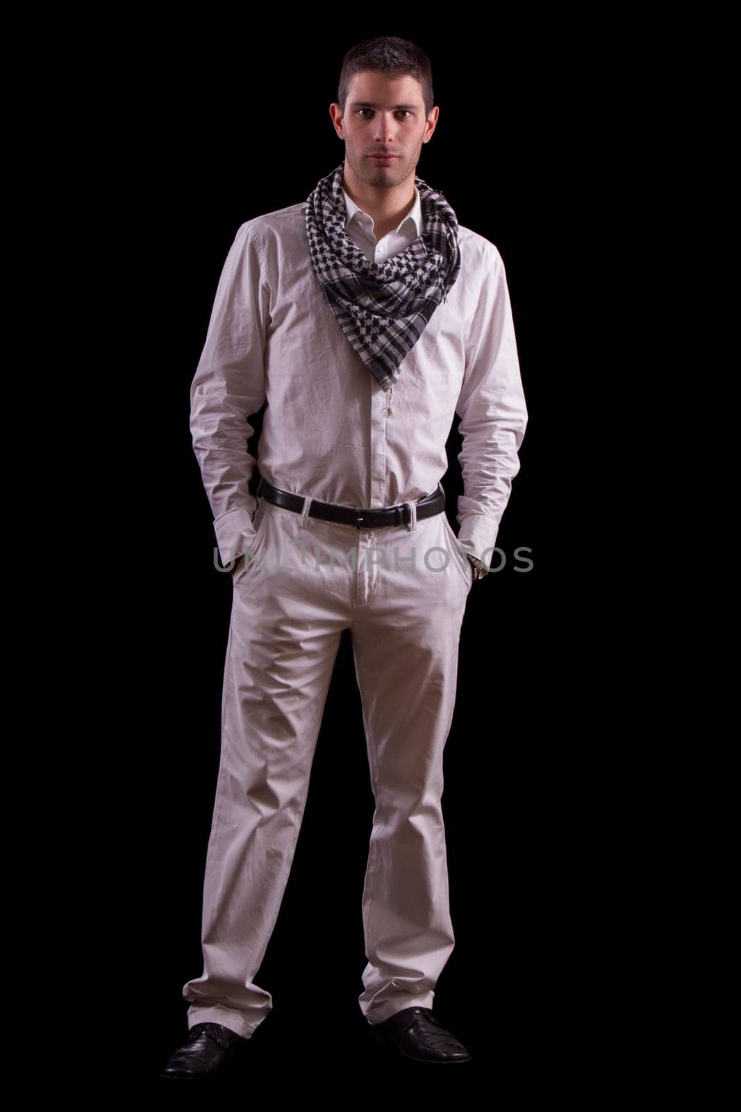 View of a young urban styled fashioned man standing isolated on a black background.