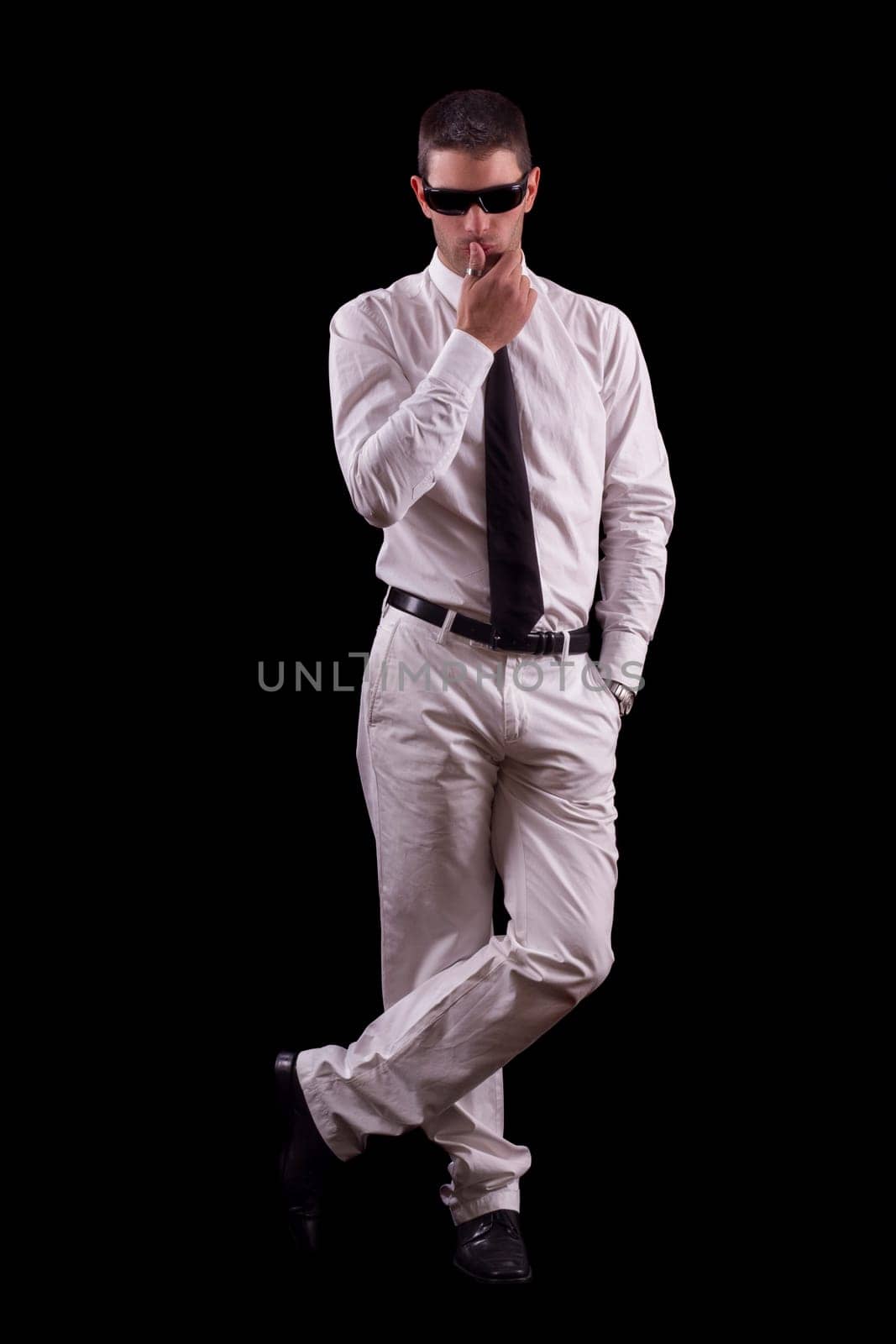 View of a handsome young man on a white suit with tie isolated on a black background.
