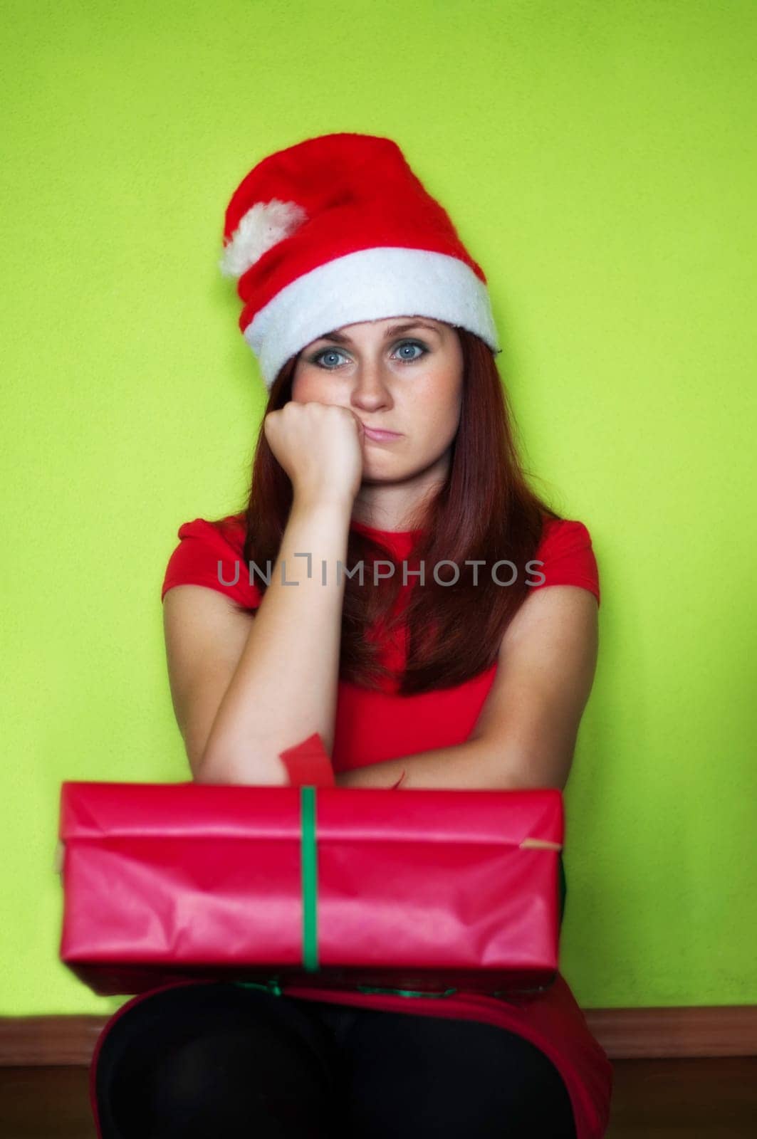 bored and disappointed woman holding a present on green wall
