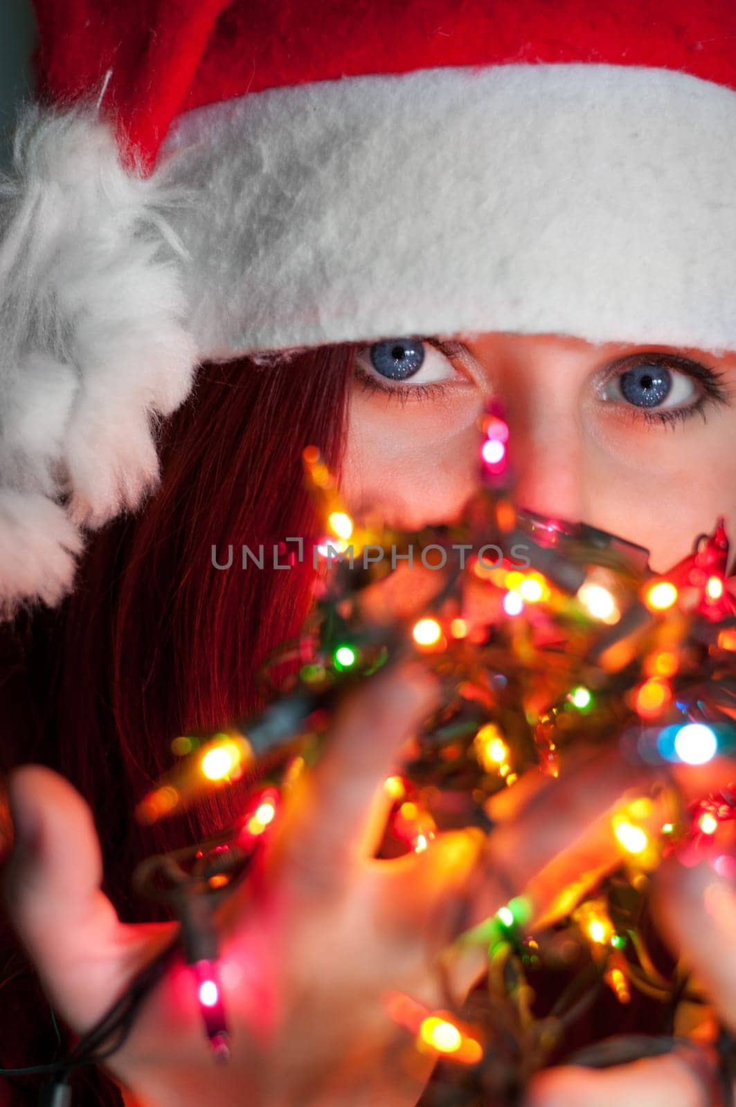 woman with christmas garland lights close up on eyes