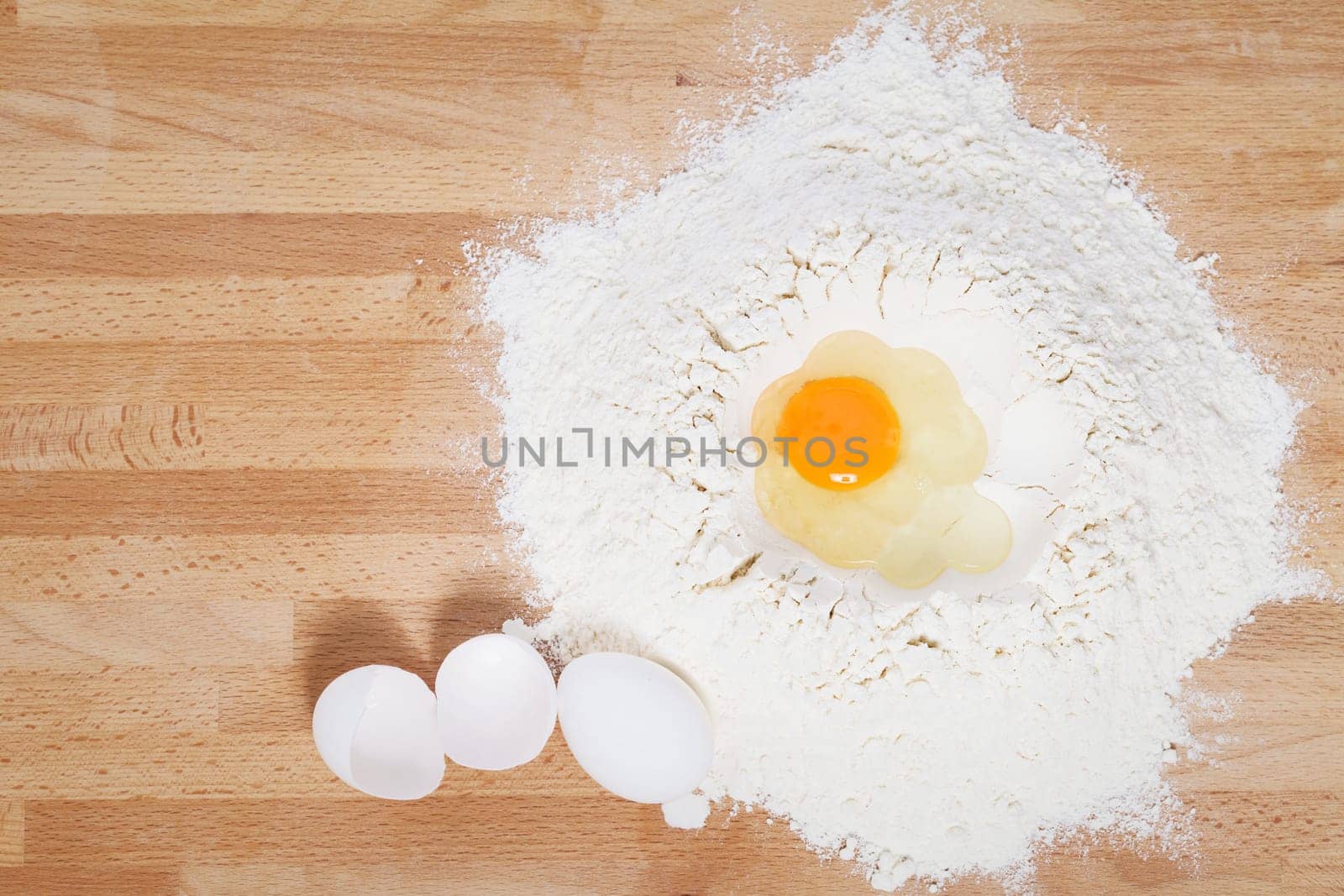 Egg in flour with eggs next to it from above on wooden ground