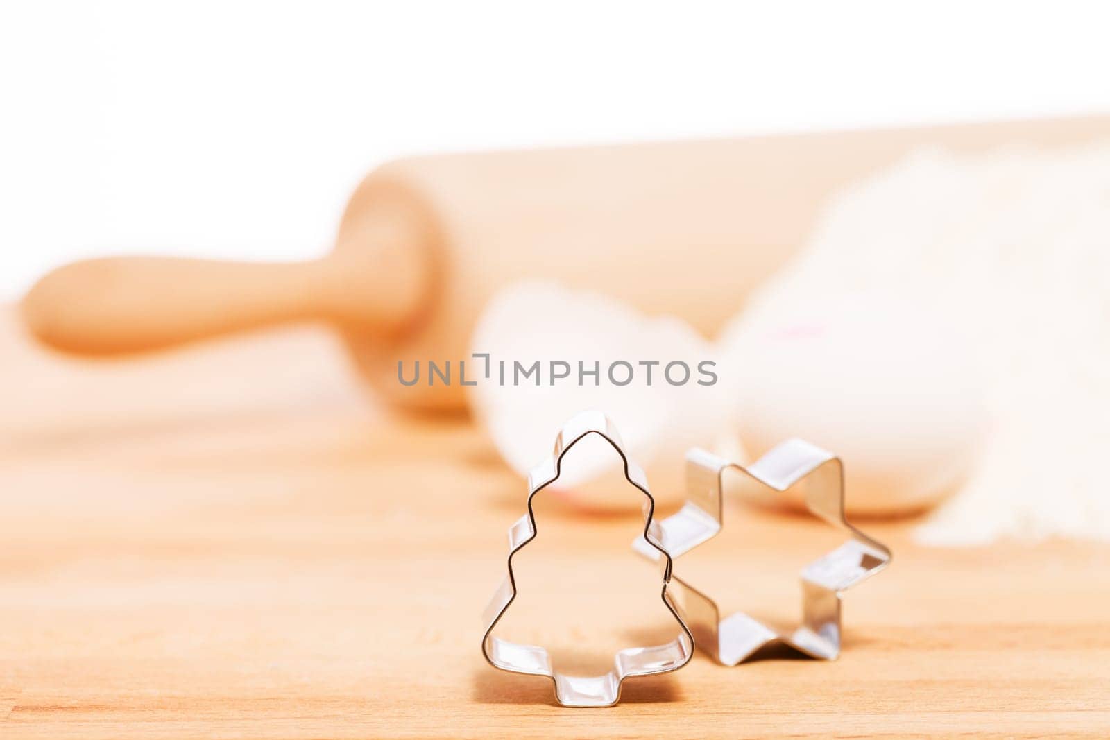 Close-up Christmas tree cookie cutter in front of baking utensils