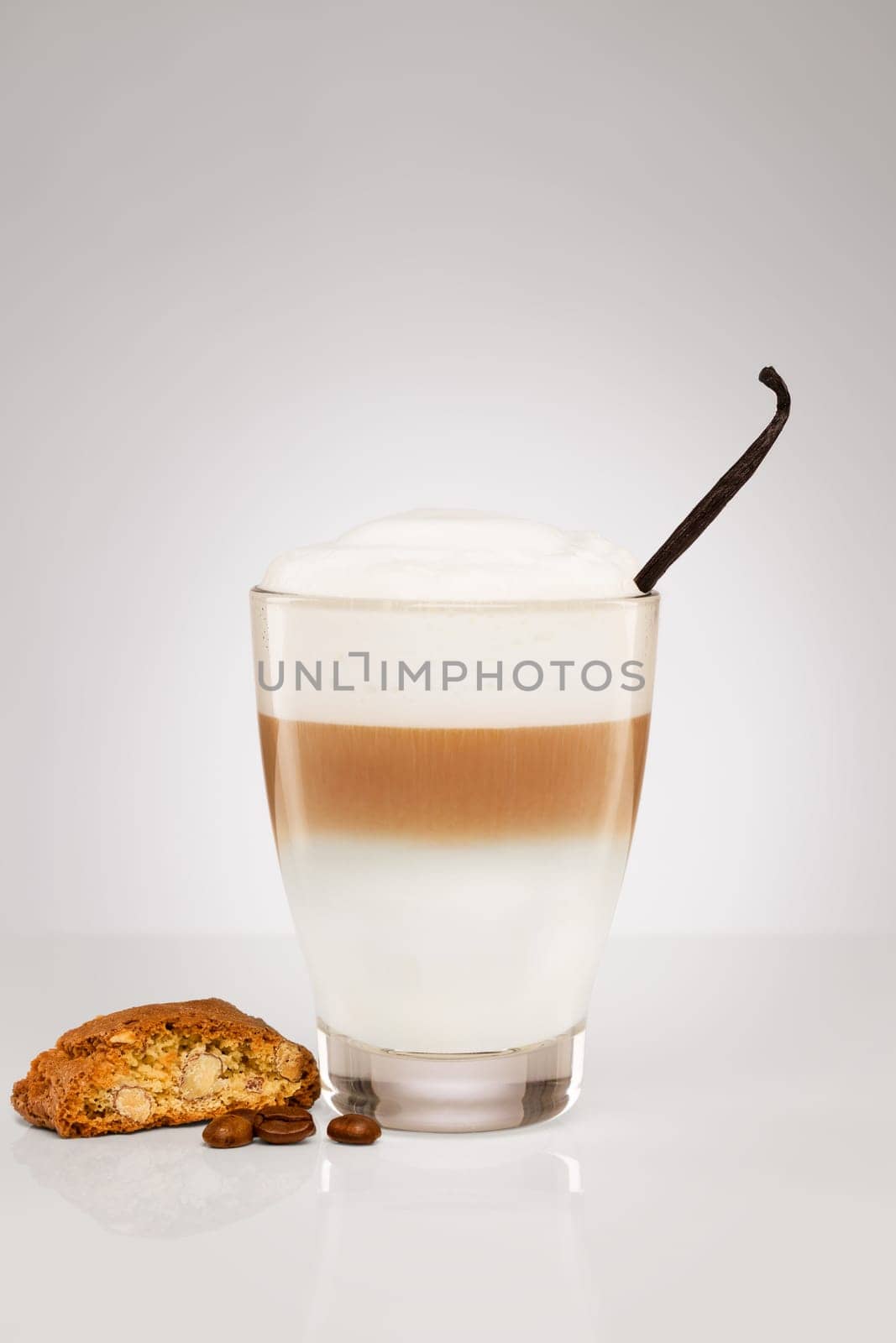 Latte macchiato with vanilla and cantuccini biscuit on grey background