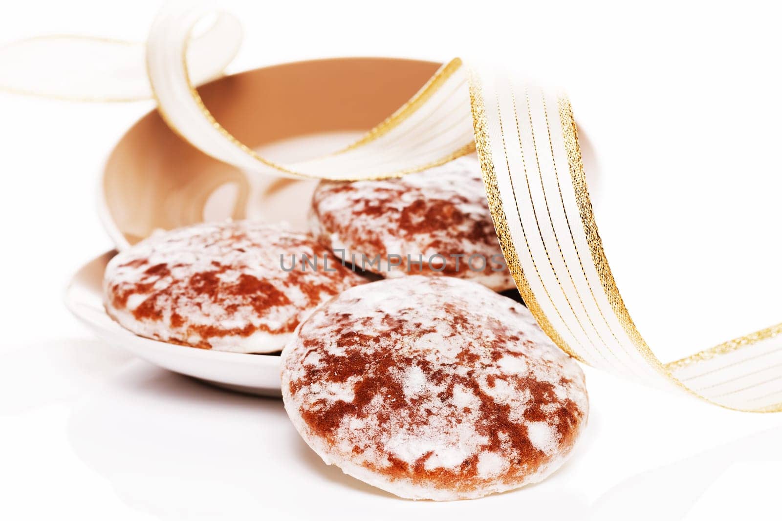 Gingerbread slides from brown plates with golden ribbon against a white background