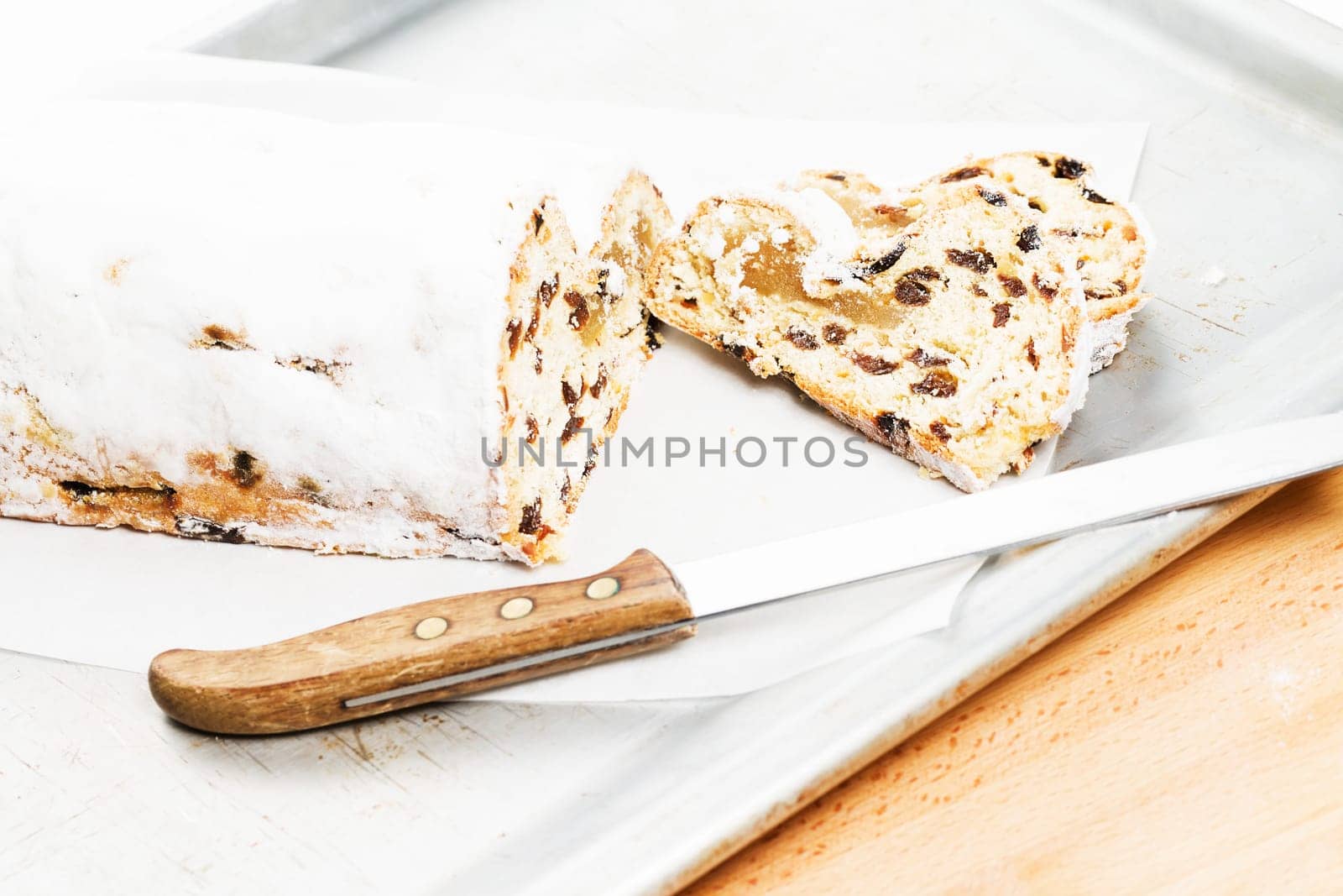 Christmas stollen with knife on silver metal baking tray