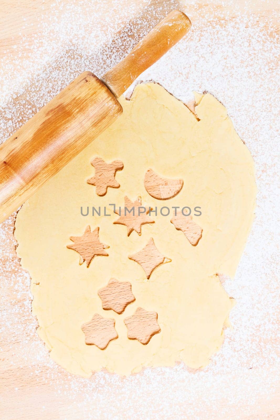 Cookies cut out of dough for Christmas with rolling pin from above