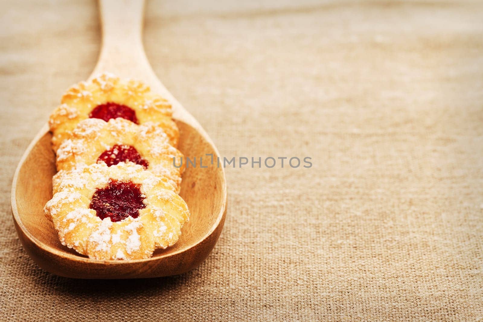 Christmas cookies with jam on a wooden spoon on linen fabric