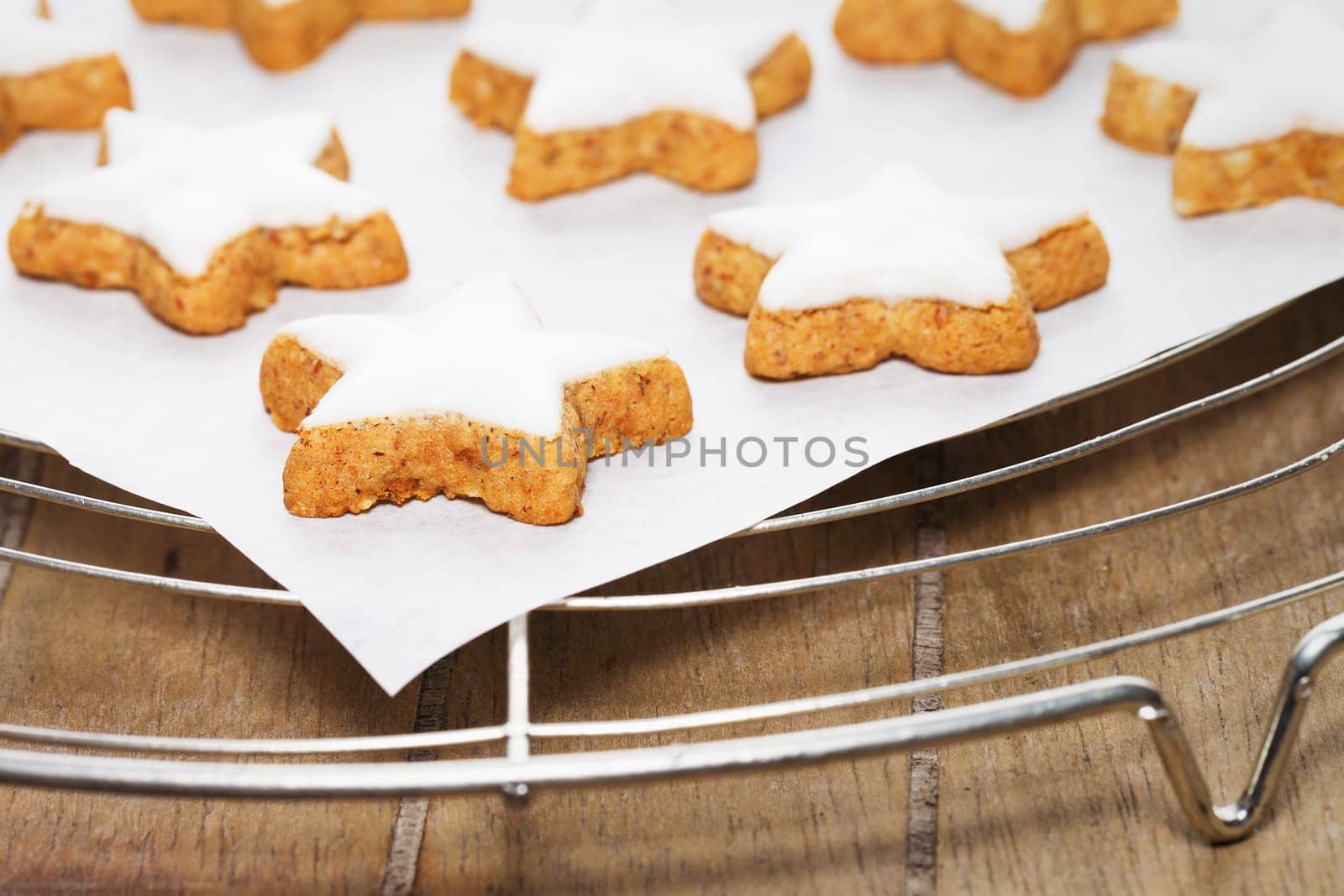 Cinnamon stars on baking paper on cake rack on wood