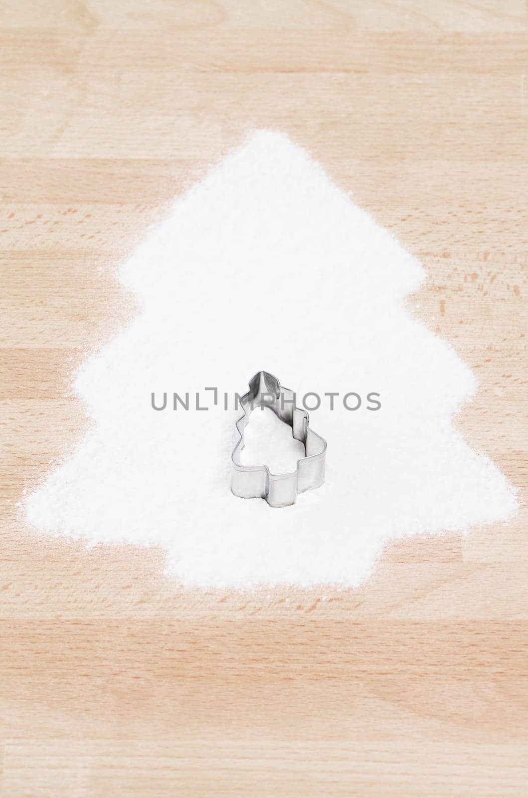 Christmas tree made of flour with cookie cutter in Christmas tree shape on wooden ground